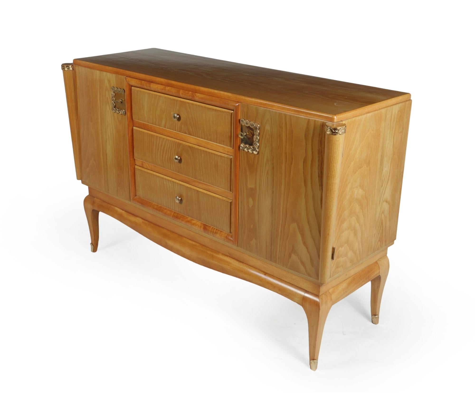 A French produced Art Deco sideboard wit ha central run of drawers and cupboards either side the and standing on a shaped base and saber leg the sideboard is covered in coated brass that has some light scratches, both doors are lockable and has two