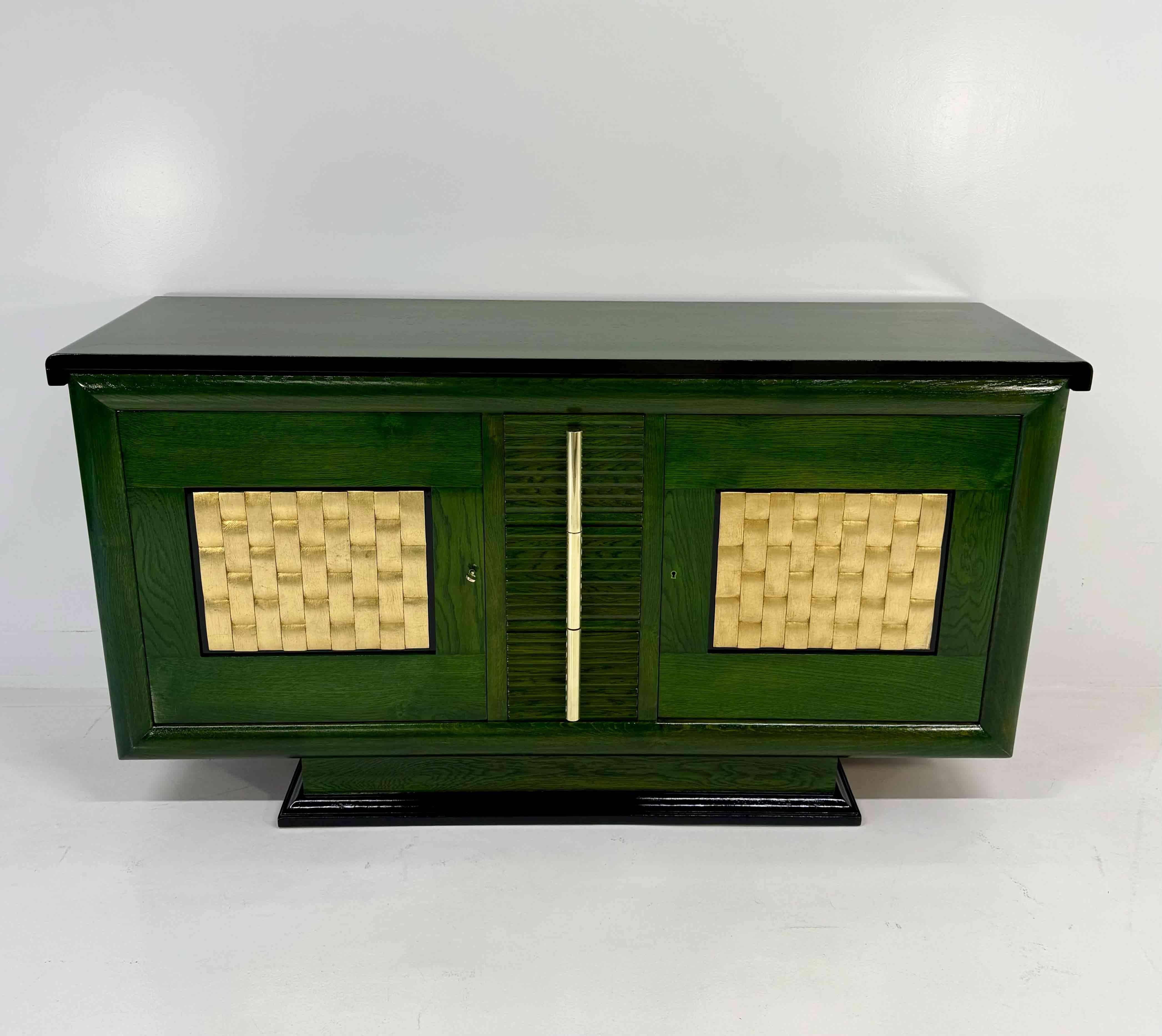 Elegantes französisches Art-Déco-Sideboard aus den 1930er Jahren aus grün anilingefärbter Eiche mit schlanken, schwarz ebonisierten Profilen.
Auf der Vorderseite befinden sich zwei große Türen mit raffinierten, blattvergoldeten Paneelen, während der