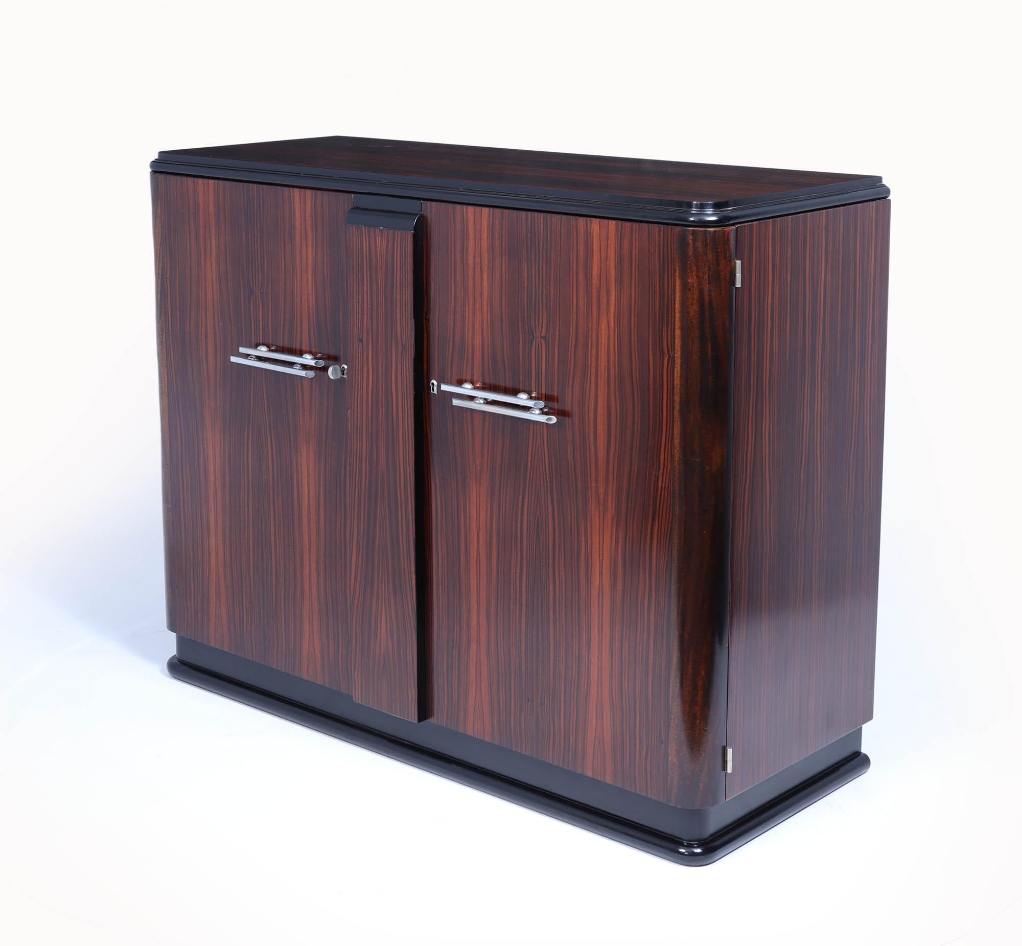 French Art Deco Sideboard 
This stunning French Art Deco sideboard, a masterpiece crafted in exquisite Macassar ebony. Its striking design is complemented by a sleek black lacquer base and elegant nickel-plated handles, making it an eye-catching