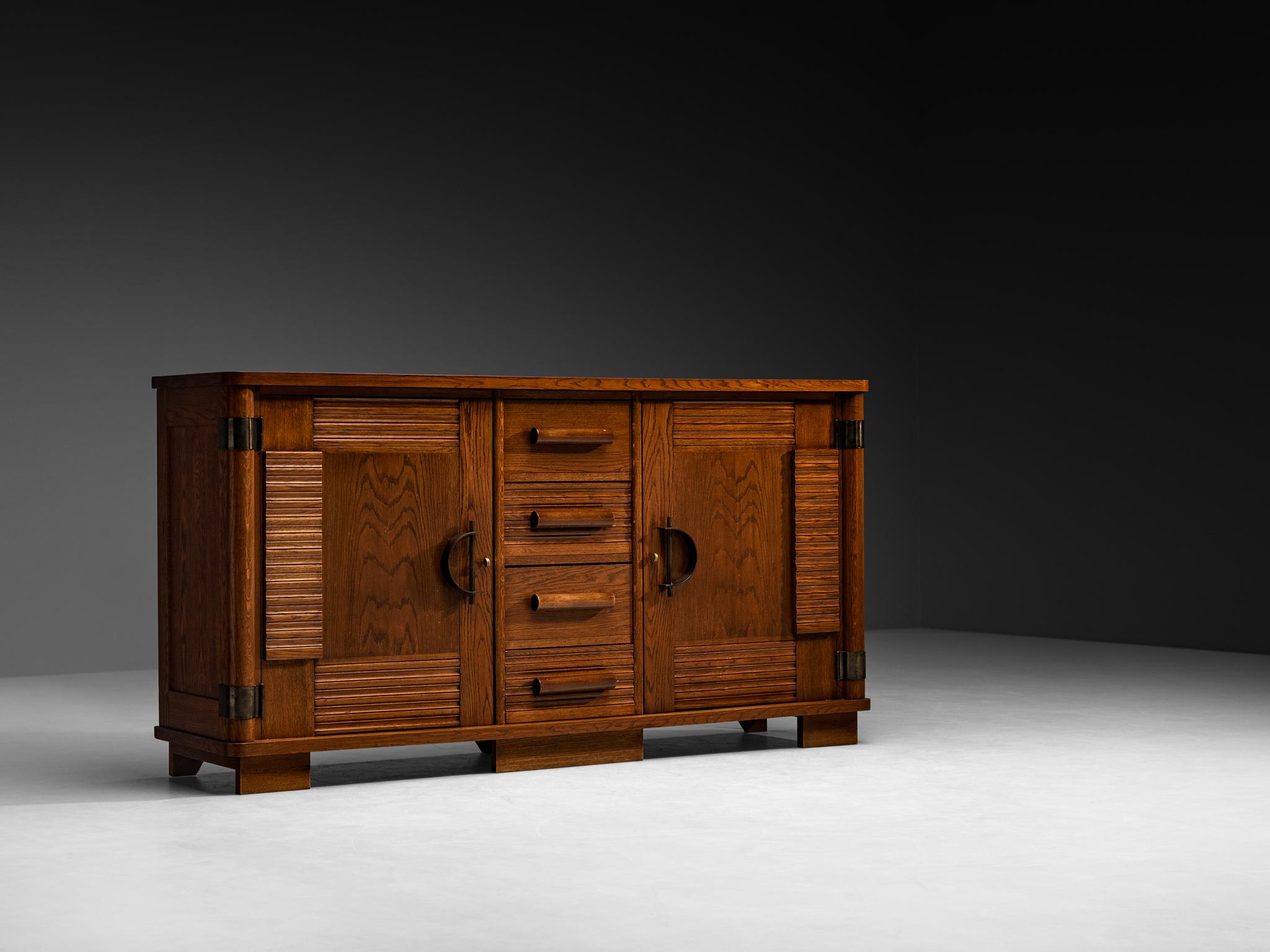 Sideboard, oak, brass, France, 1930s

This French sideboard from the 1930s is crafted in oak and features strong geometric lines and finely worked surfaces. The fluted panels framing the doors and drawers add refined contrast. Inside, the double