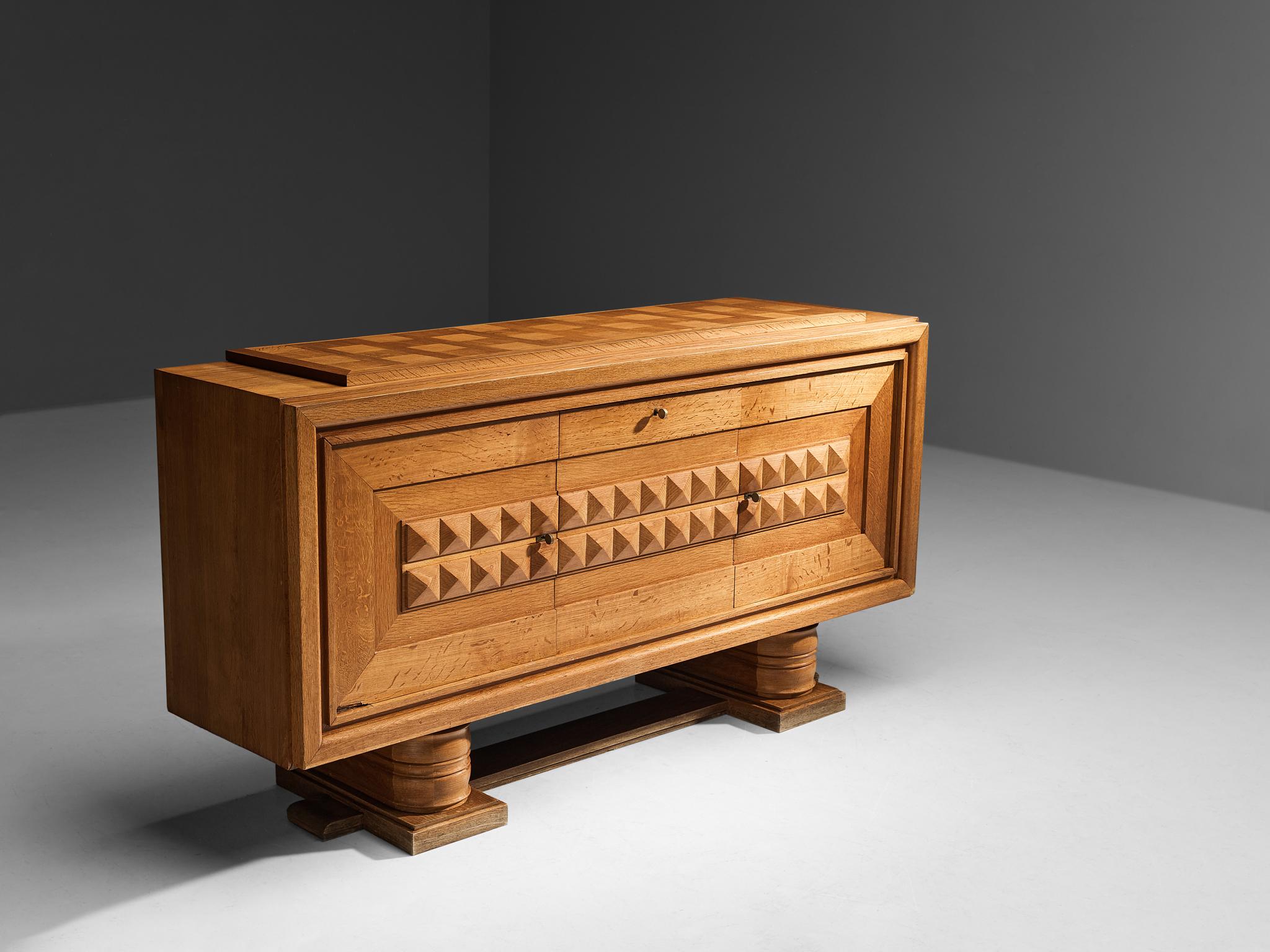 Attributed to Charles Dudouyt, sideboard, oak, oak veneer, brass, France 1940s.

This exceptional credenza undoubtedly breathes the Late Art Deco Period of the 1940s. Excellent craftsmanship is combined with a well-balanced eye for the composition