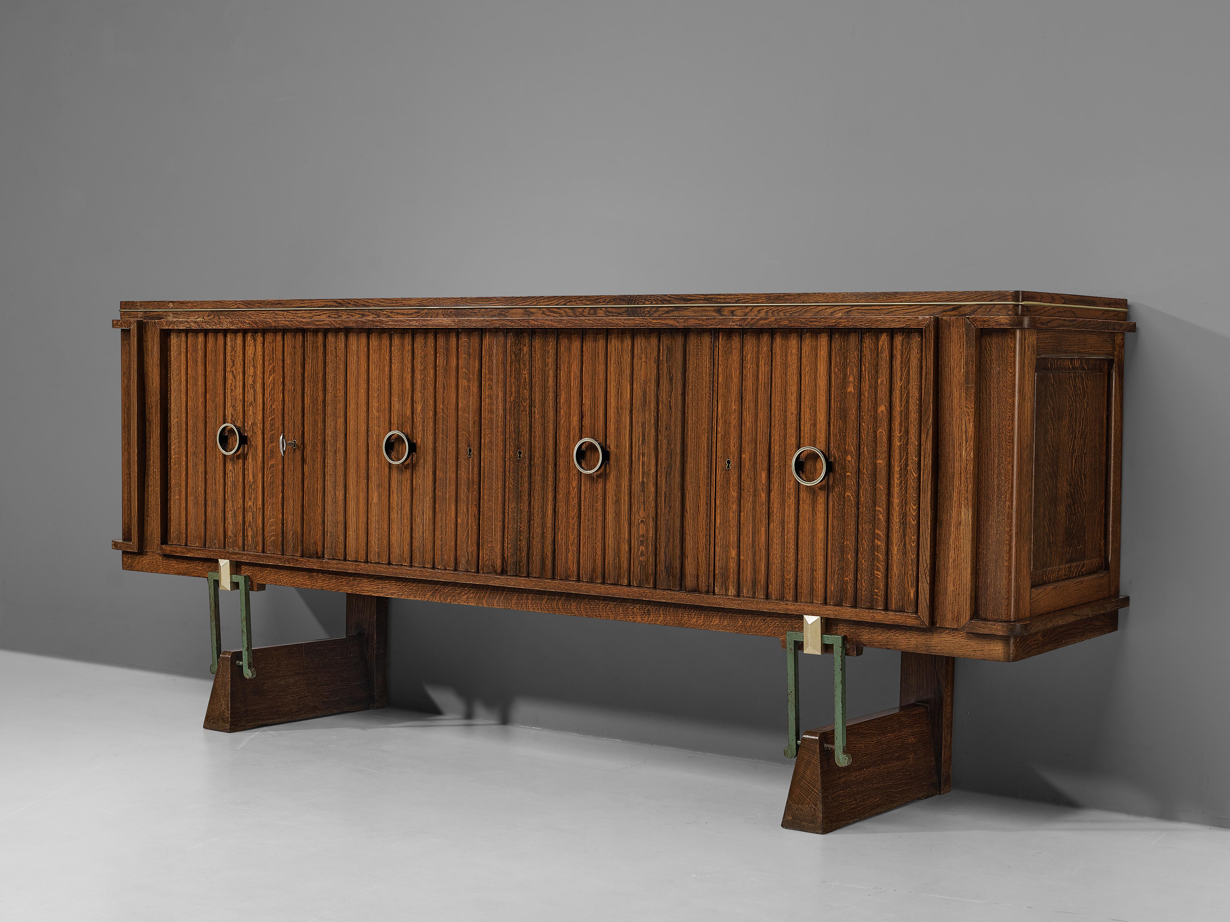 Sideboard, oak, brass, metal, France, 1940s

This lovely elongated sideboard features four door panels with vertical wood carvings, accompanied with circular brass handles. A beautiful detail that makes it such a well-designed piece, are the