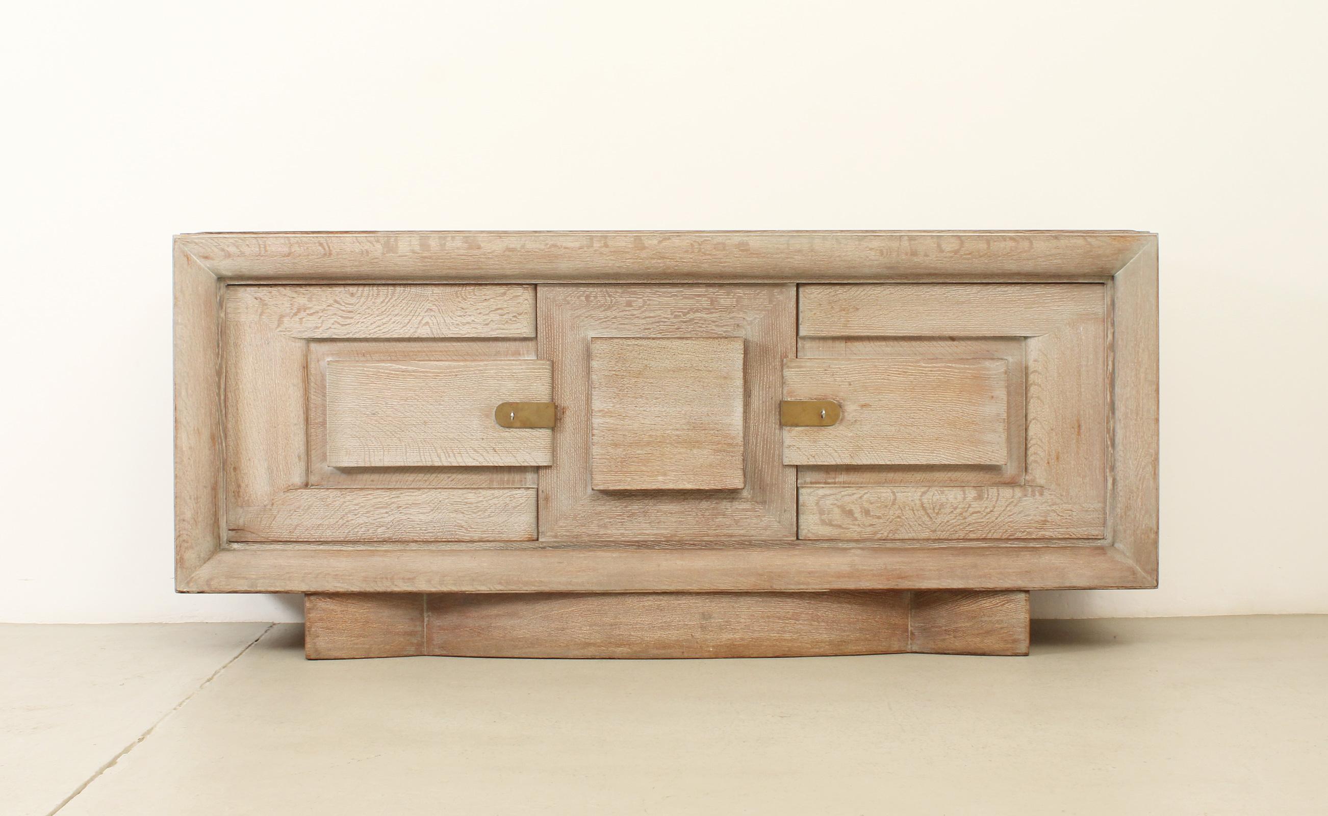 French Art Deco sideboard in the style of Charles Dudouyt, 1940's. Solid cerused oak wood and brass fittings. Three compartments with internal shelves and two drawers, the central front piece can be moved to either side. 