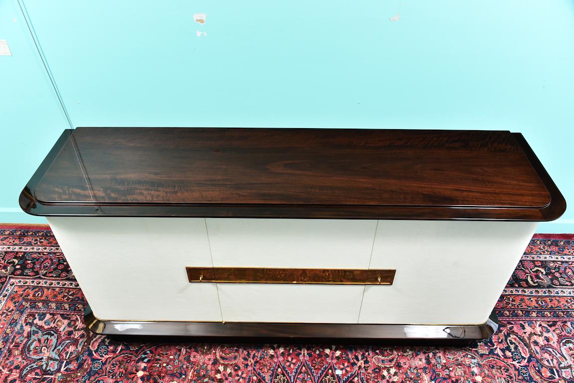 French Art Deco sideboard in walnut with white leather 
 Sideboard is made out of fine walnut wood. Beautiful grain is displayed on the top of it. Middle section is covered with white cowhide. There are 2 keyed drawers. Resting on rectangular wood