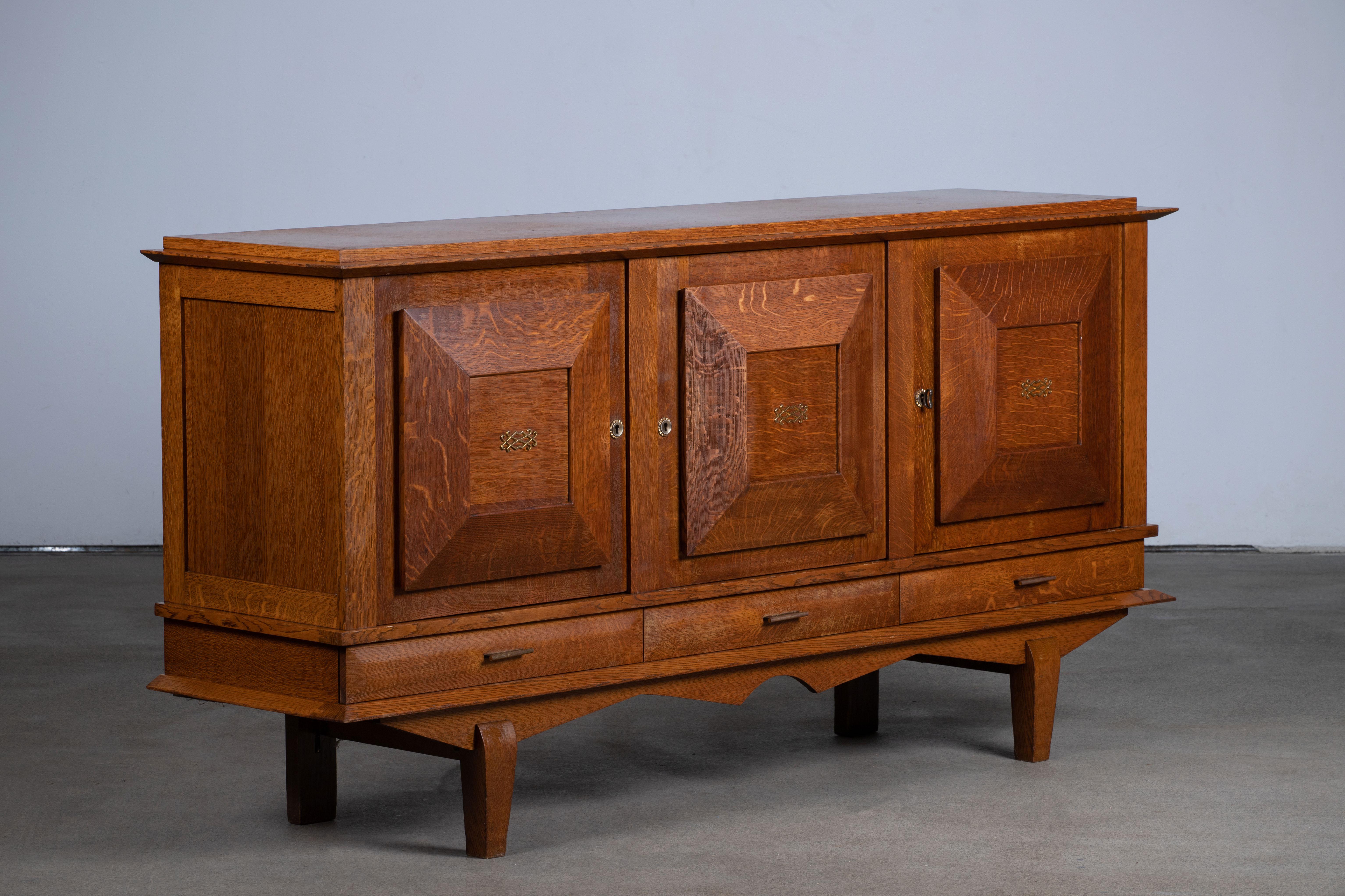 Credenza, solid oak, France, 1940s.
Large Art Deco Brutalist sideboard. 
The credenza consists of two storage facilities covered with very detailed designed door panels and four drawers.
 