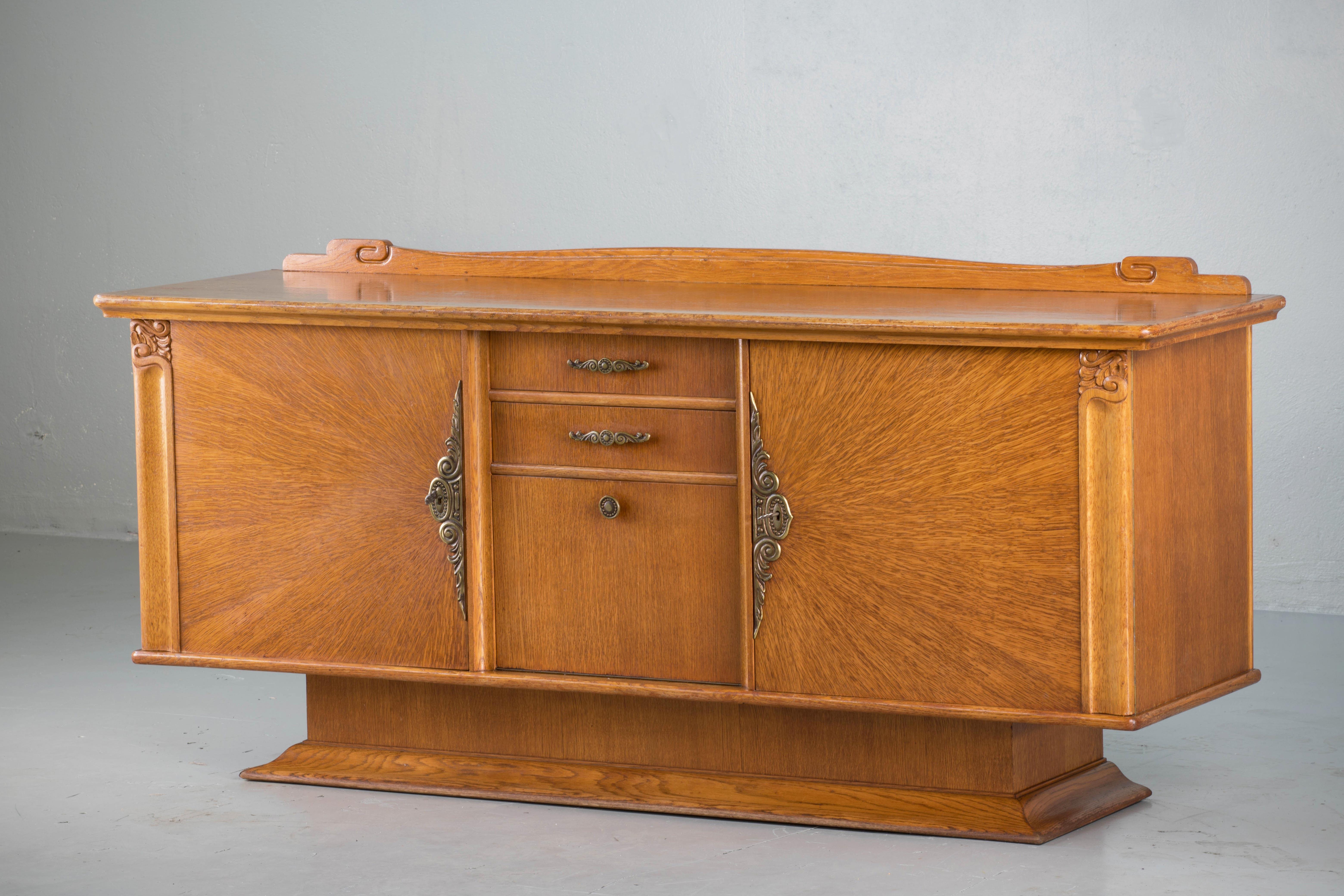 French Art Deco sideboard, credenza, with bar cabinet. The sideboard features stunning oakwood grain with a fan veneer. It offers ample storage, with shelve behind two doors on the left and a dovetailed drawer and additional shelving behind two