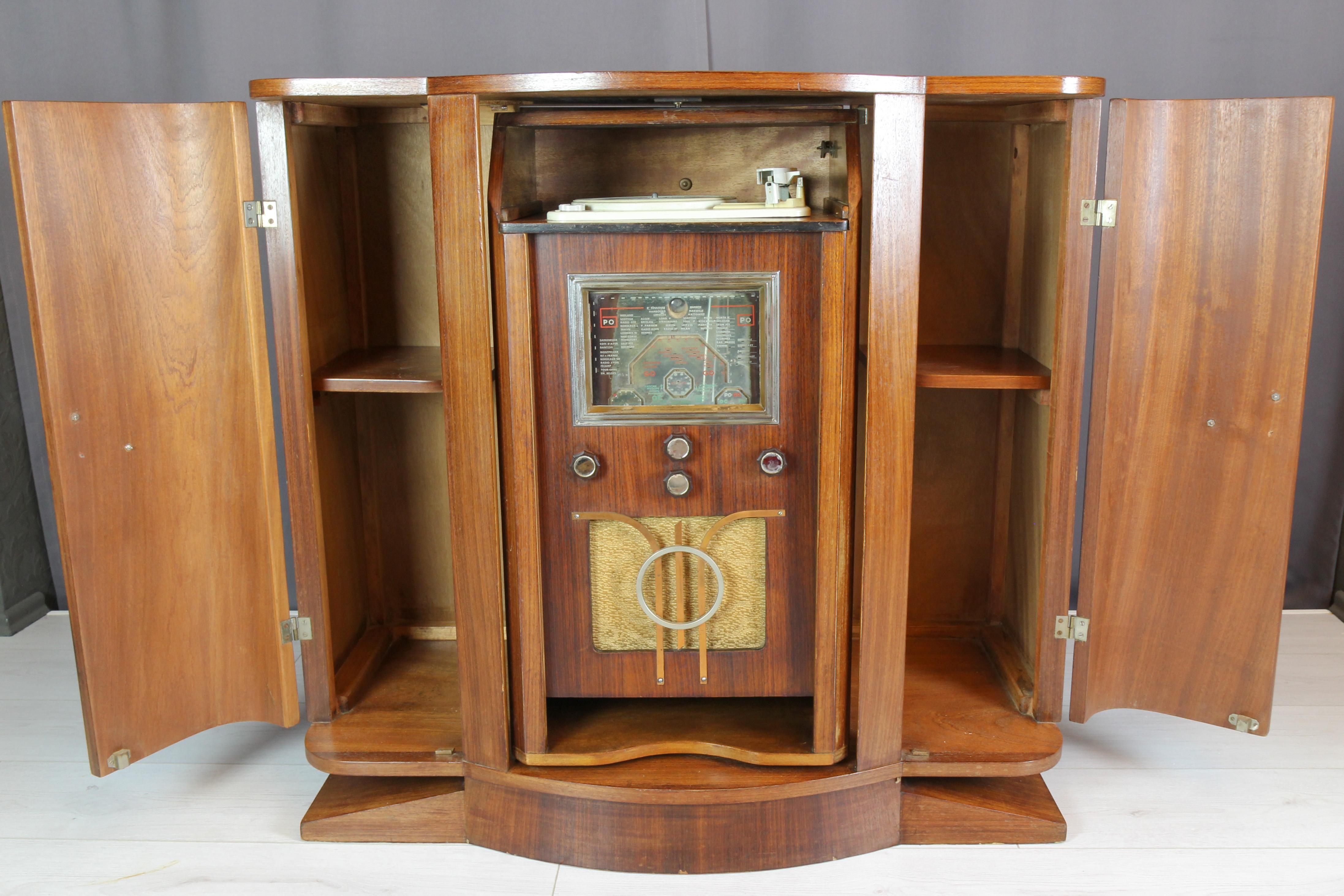 Art Deco Sideboard with Radio and Record Player, France, 1930s.
Beautifully sculpted Art Deco sideboard in blockboard and walnut veneer. The rotatable drawer-look middle section with four brass knobs opens a set consisting of a radio and a record