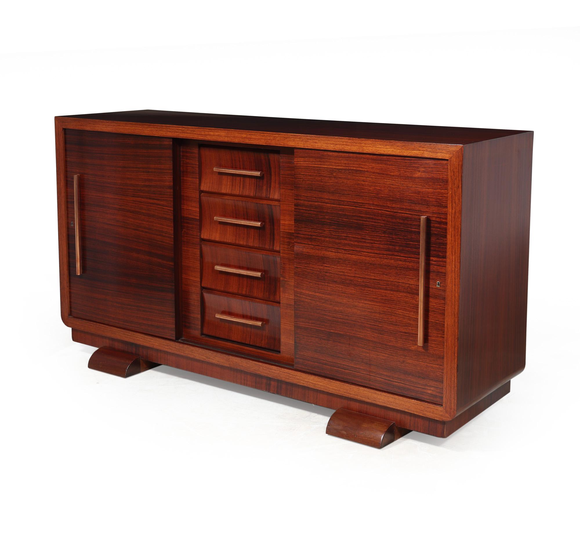 FRENCH ART DECO SIDEBOARD 
An Art Deco sideboard with two sliding doors and four central concave drawers with copper handles standing on sled feet, behind are adjustable height shelves in either side, the sideboard has been fully polished and is in