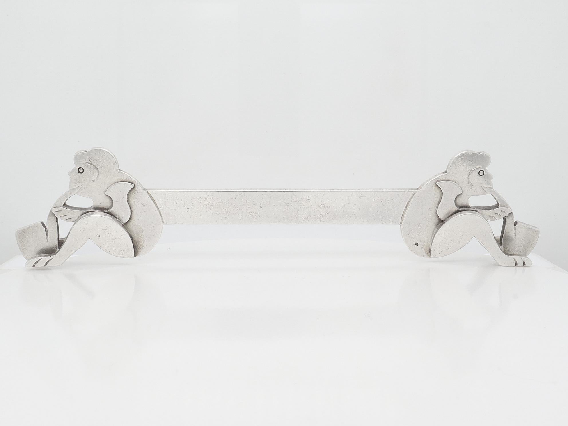 Un bel poggiacoltelli francese Art Déco firmato.

In argento secondo standard francese.

Di Louis Mathey, il famoso argentiere francese dell'Art Déco.

A forma di barra piatta che termina con due scimmie sedute che fumano ciascuna una pipa.

Il