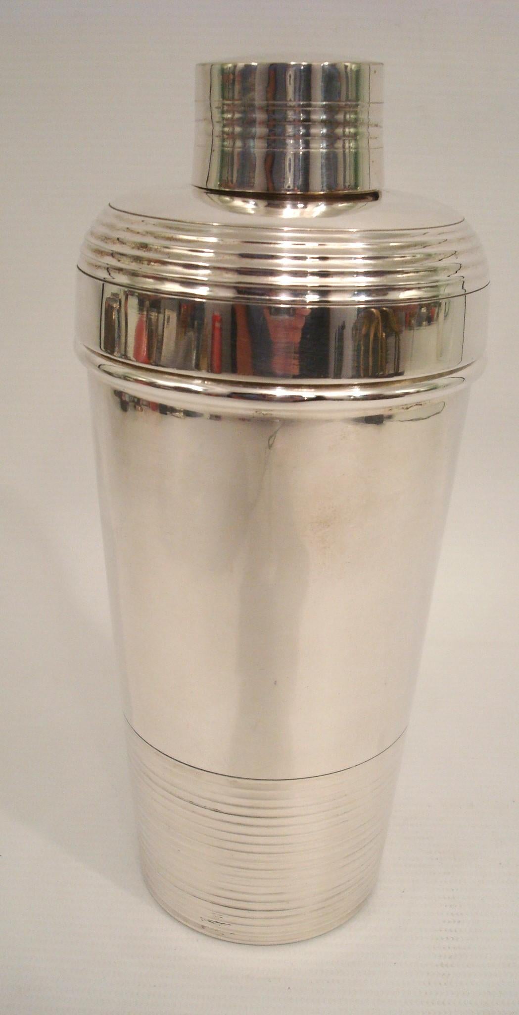 This fabulous French Art Deco silver plate cylindrical cocktail or Martini shaker was crafted by Hermes Paris, in the 1920s. The three-sectioned cocktail shaker has a removable cap and strainer. The piece boasts a lovely geometric shape with a