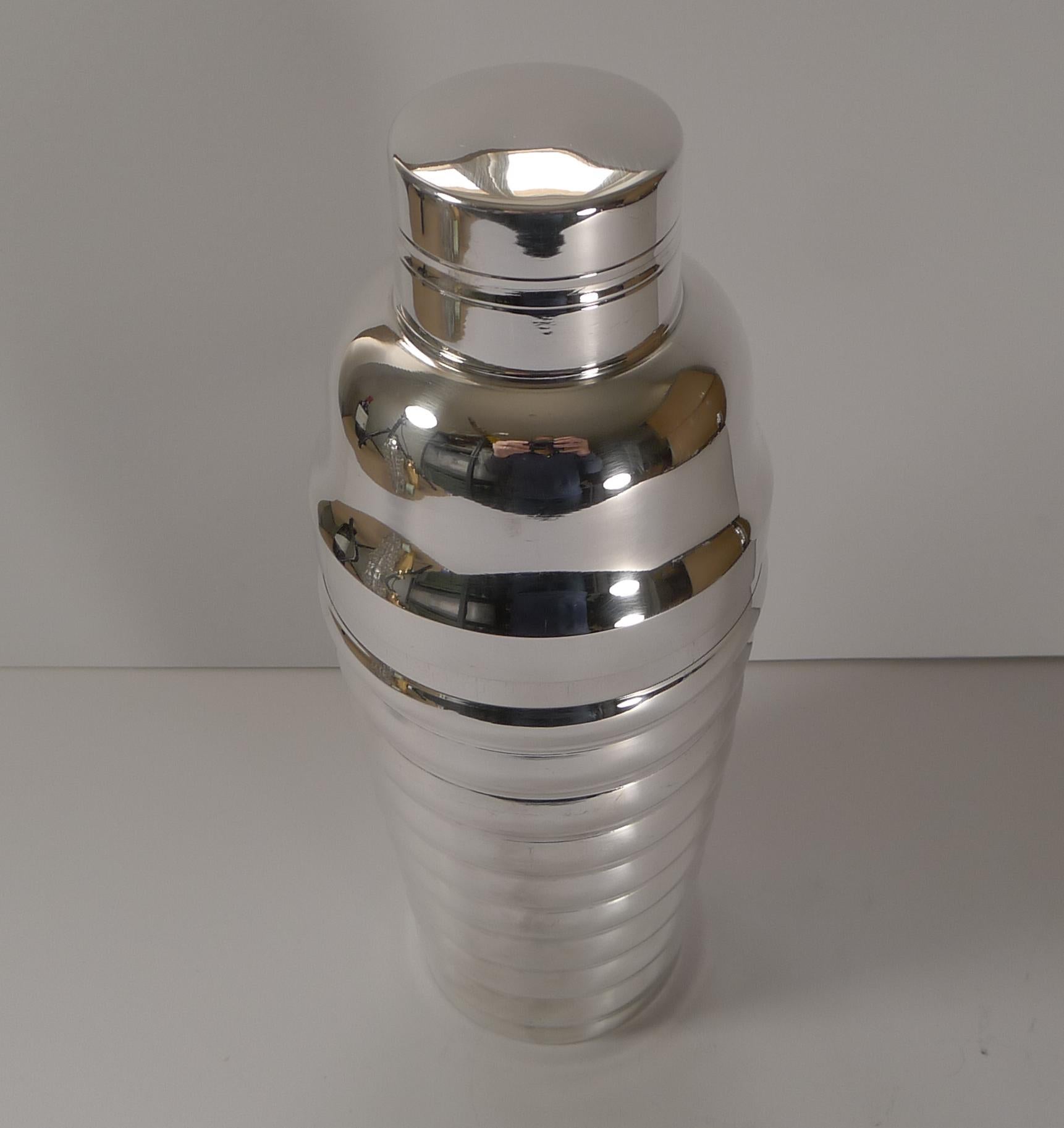 A great looking cocktail shaker, French in origin and in silver plate dating to the Art Deco era, c. 1930's.

A wonderful and unusual design with a fully ribbed body. The underside is signed by the silversmith, a square, two stars and 