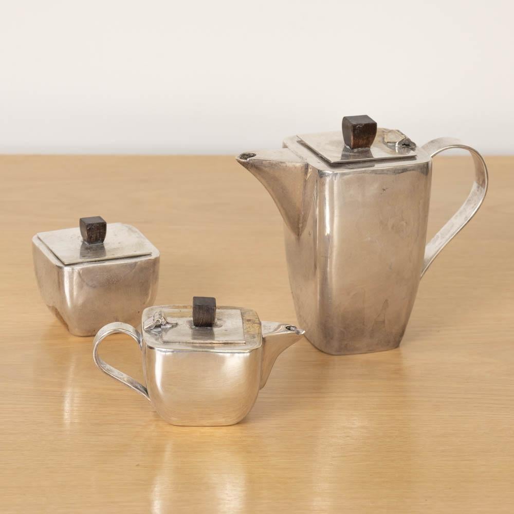 Unique Art Deco silver plate tea set made from France, 1930s. Heavy silver plate with wood handle detail. Set includes 1x tea pot with lid, 1x sugar bowl with lid, and 1x creamer bowl. Original finish shows great age and patina. Pieces measure,