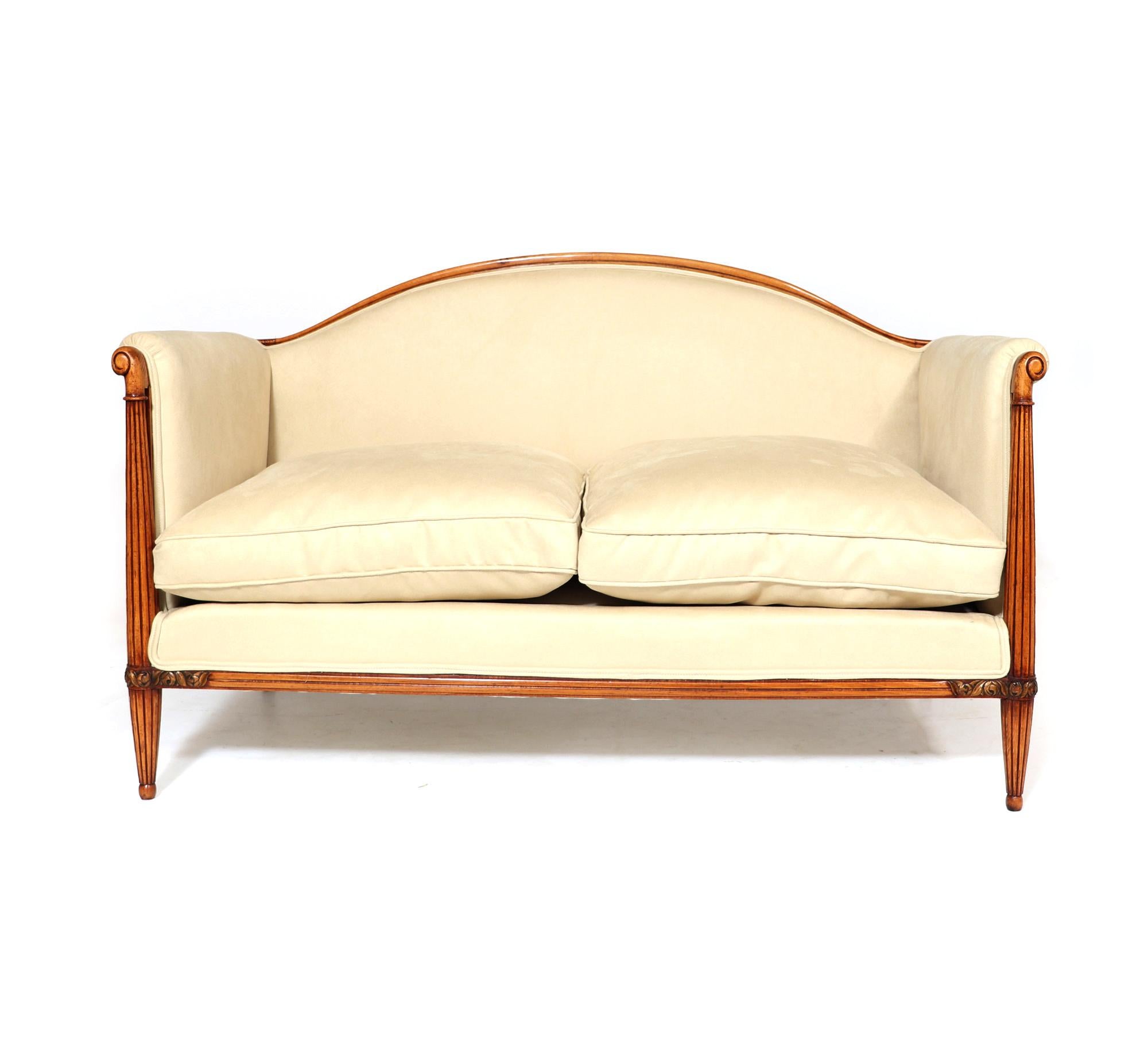 A fine quality French art deco sofa with turned reeded leg with shaped top and gilded carving polished show wood and fully upholstered, coil sprung with down filled cushions and covered in soft cream velvety suede type fabric that is stain resistant