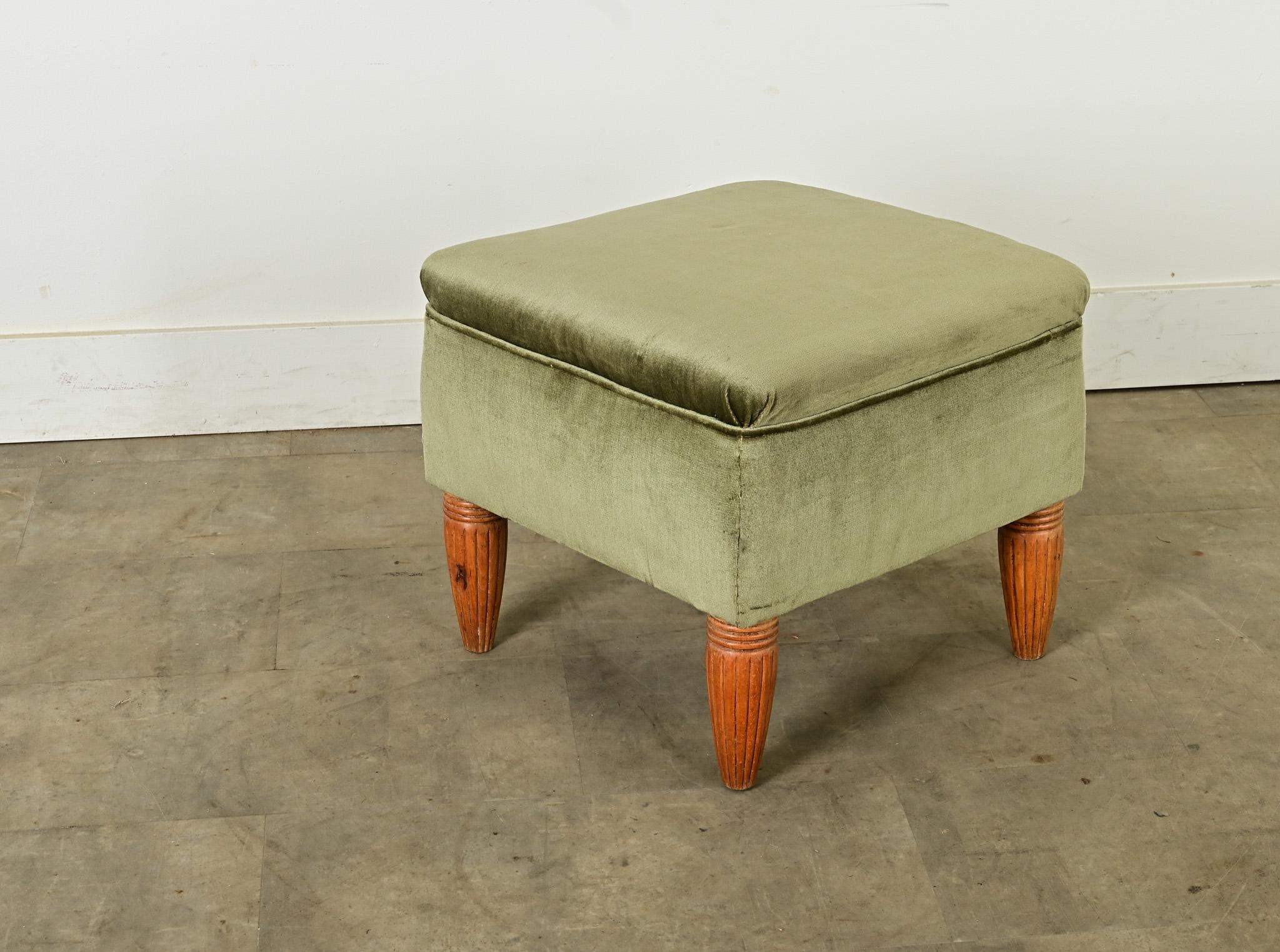 Joli pouf, ottoman ou tabouret de la période Art déco avec d'élégants pieds sculptés à la main et un revêtement en velours vert sauge. Sa construction en bois massif est entièrement enveloppée de tissu, la couronne de l'assise surplombant le caisson
