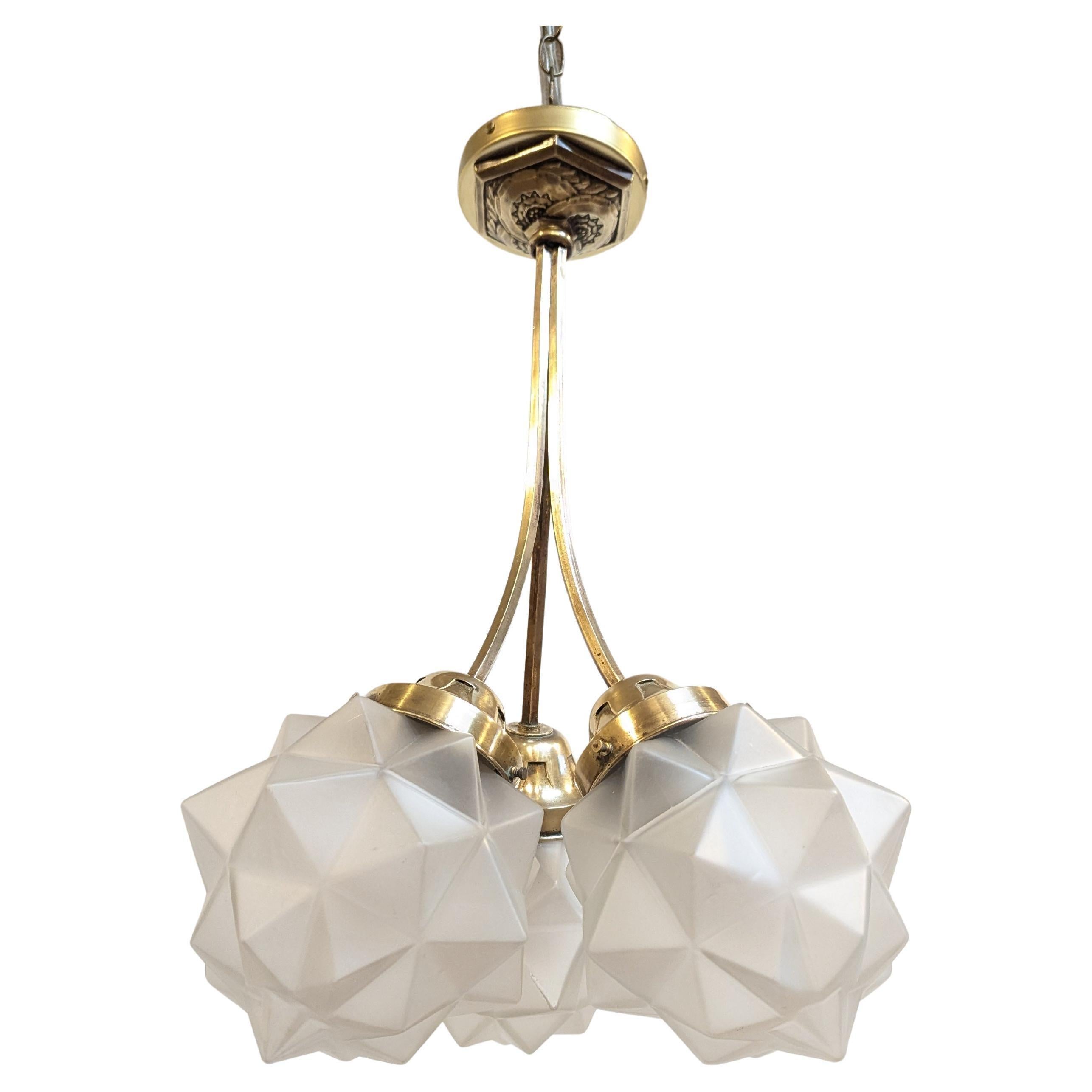 French Art Deco Brass 
Frosted Molded Glass Chandelier.  Art Deco Brass Chandelier with molded Glass Star Polyhedron shades.   Beautiful having three frosted molded glass Star polyhedron shaped shades suspended from three solid brass canisters
