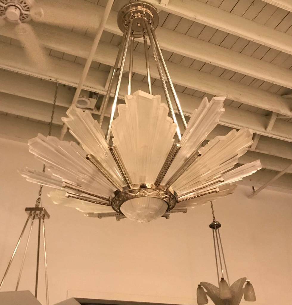 French Art Deco starburst chandelier by G leleu. Having 12 outer clear frosted molded glass panels and beautiful centre bowl having geometric motif. Polished details on a silvered nickel bronze frame with a geometric design. Has been rewired for