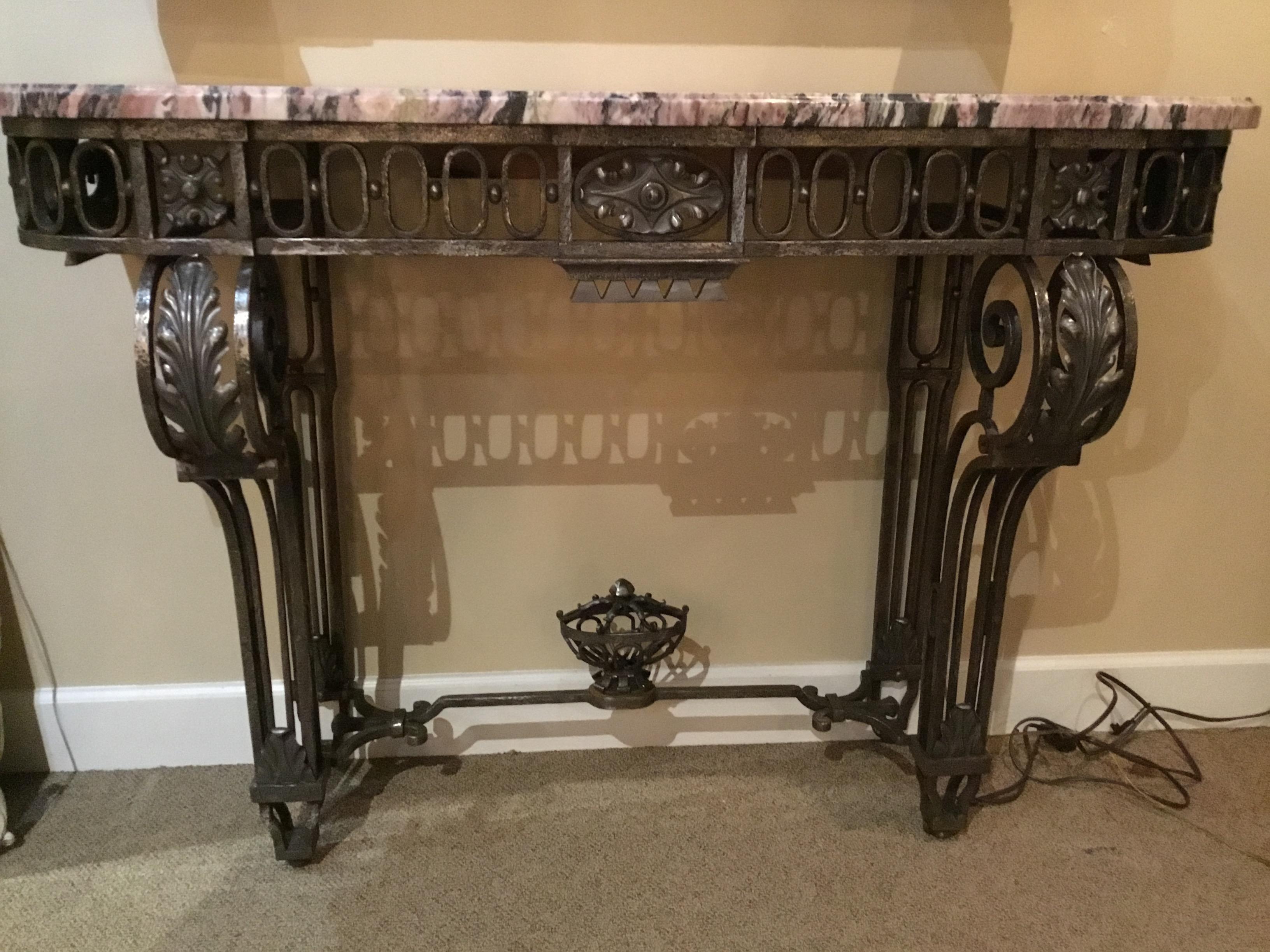 Steel console with pierced, scrolled supports, the skirt decorated with
Pierced ovals and a central panel of molded leaves, a compote-form
Finial on the base, set with. Mauve and white marble top.