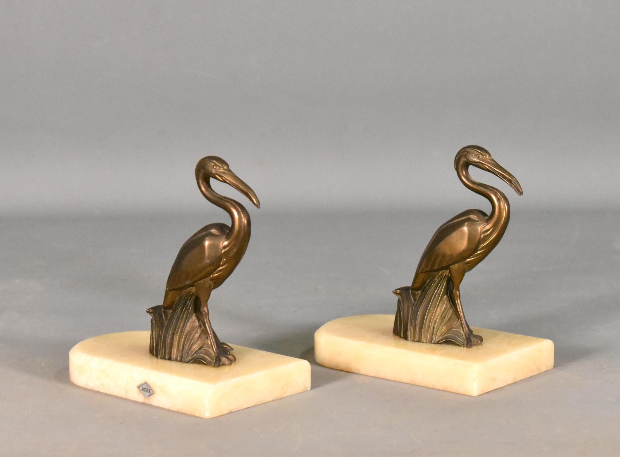 Art Deco Stork Bookends 

A delightful matching pair of Art Deco Stork Bookends cast in bronzed spelter. 

The bookends stand on polished onyx marble with bevelled edges and rounded to one end. 

The pair is finely cast with great detail and retain