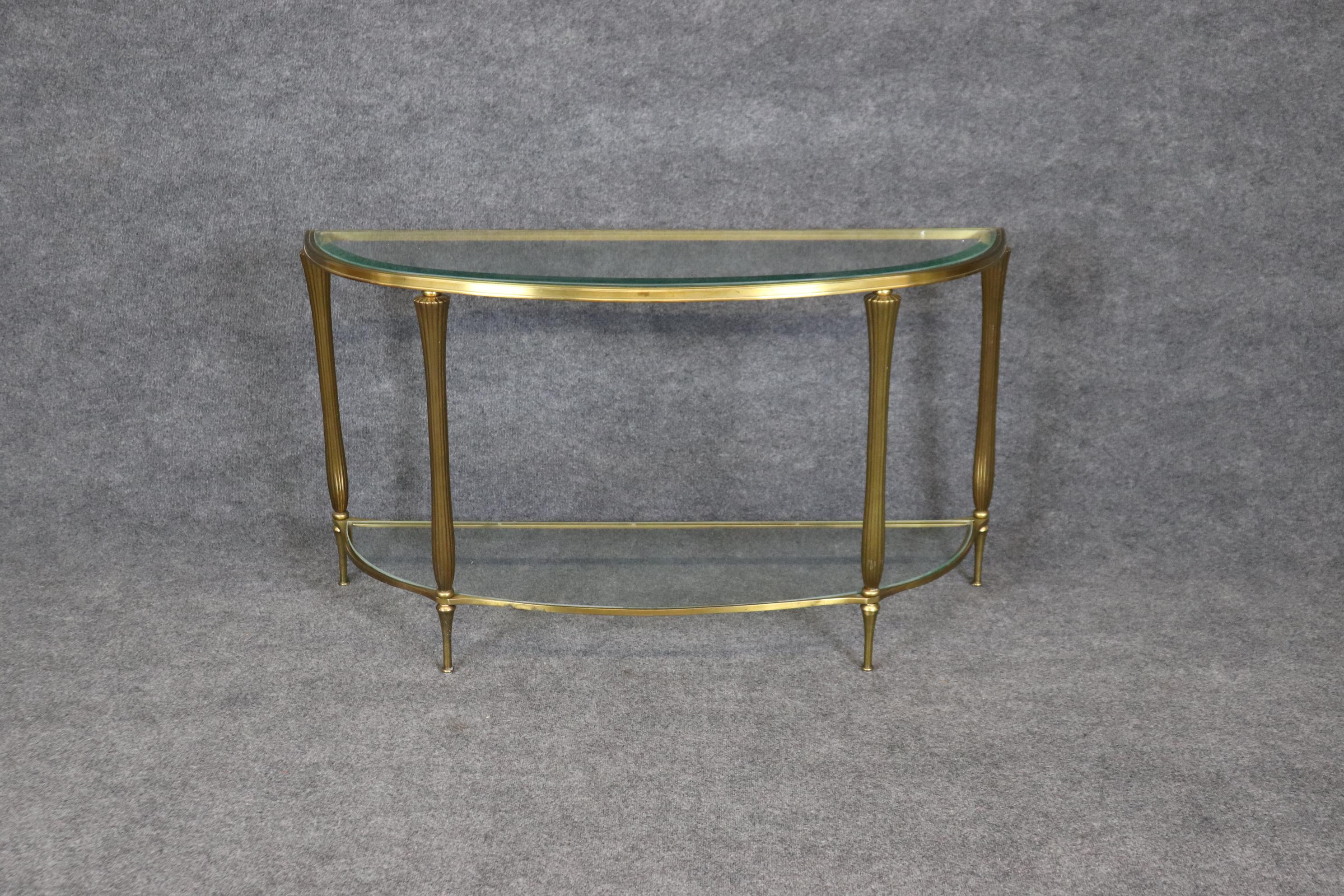 This is a fantastic Art Deco style solid brass console table with a beveled glass top. The table was most likely made by LaBarge which has these made in Italy. The table will show minor signs of oxidation which is easily polished by us or by