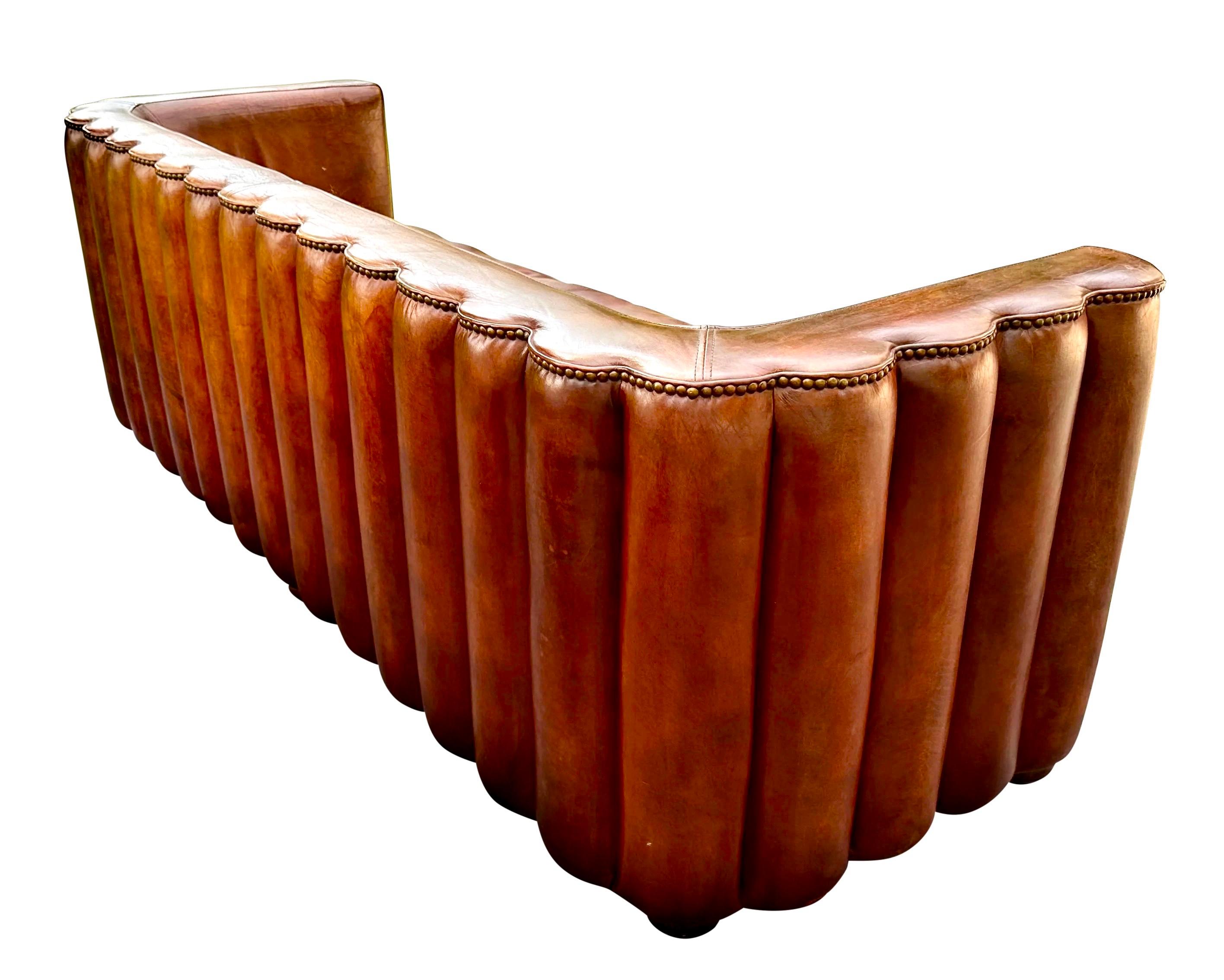 Introducing a stunning 1930’s Art Deco-inspired sofa that embodies both Modernity and Elegance. This exquisite piece features a sleek low-slung tuxedo frame, adorned with a padded channel back elegantly bordered by brass nailhead trim. Crafted from