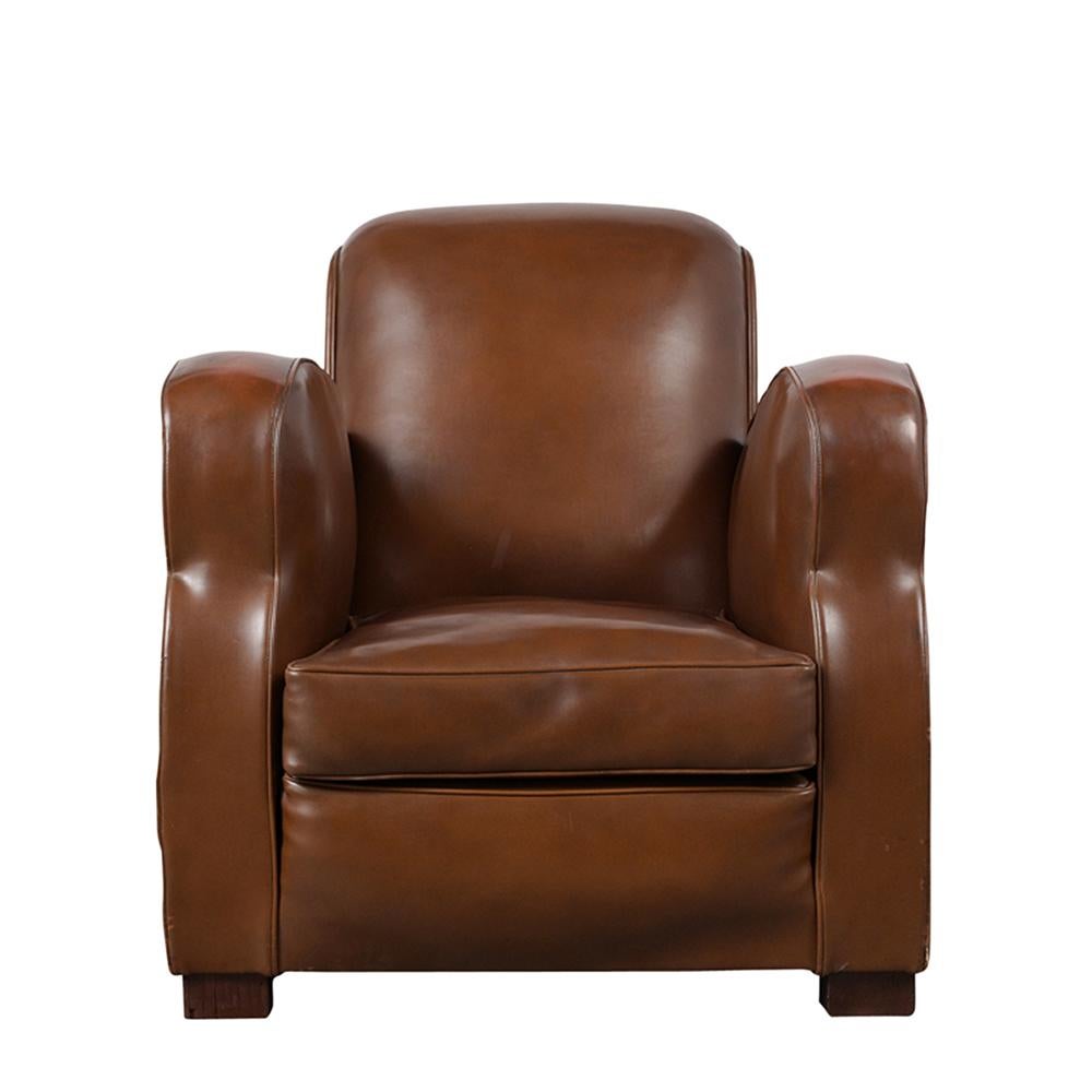 This 1950s French Art Deco Style Club Chair features the original light brown vinyl upholstery with single piping trim detail and is in good condition. The armchair features a single comfortable seat cushion and rests on carved wooden legs stained a