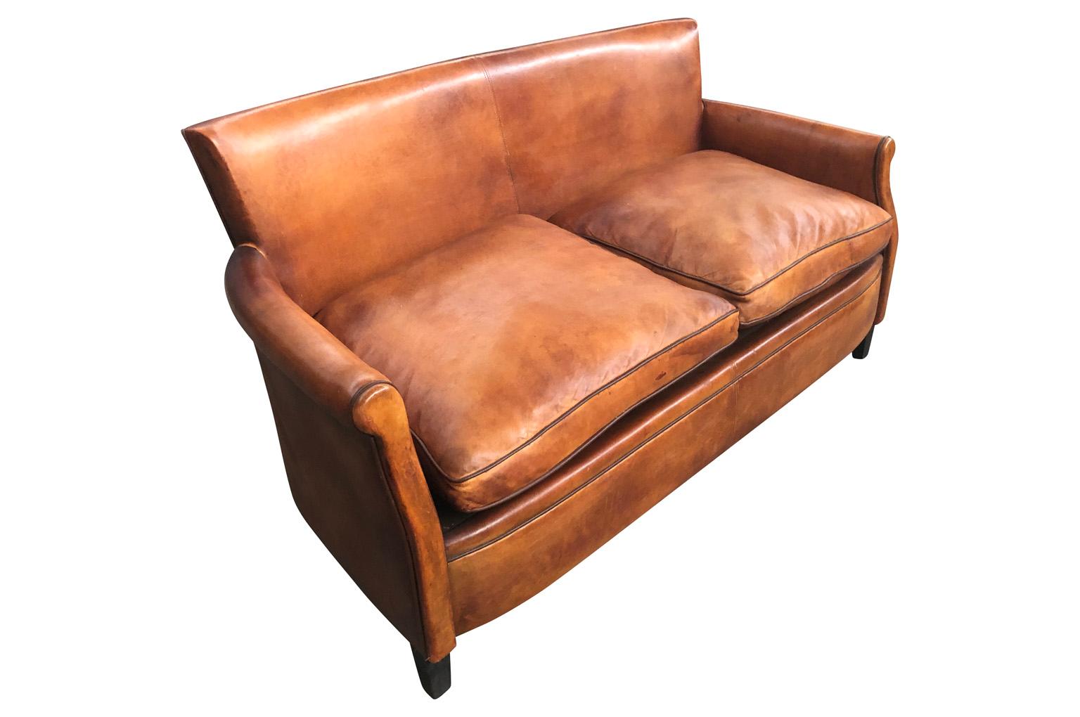 A sensational French Art Deco Style Club Sofa in beautiful leather. Terrific patina and very comfortable. Wonderful minimalist design and diminutive scale. Seat height is 18 3/4