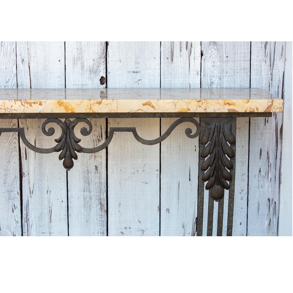Wrought Iron wall mount console table with Art Nouveau designs. The marble top has beiges and browns and sits above a simple iron apron. Two Art Deco style bracket legs support the whole.