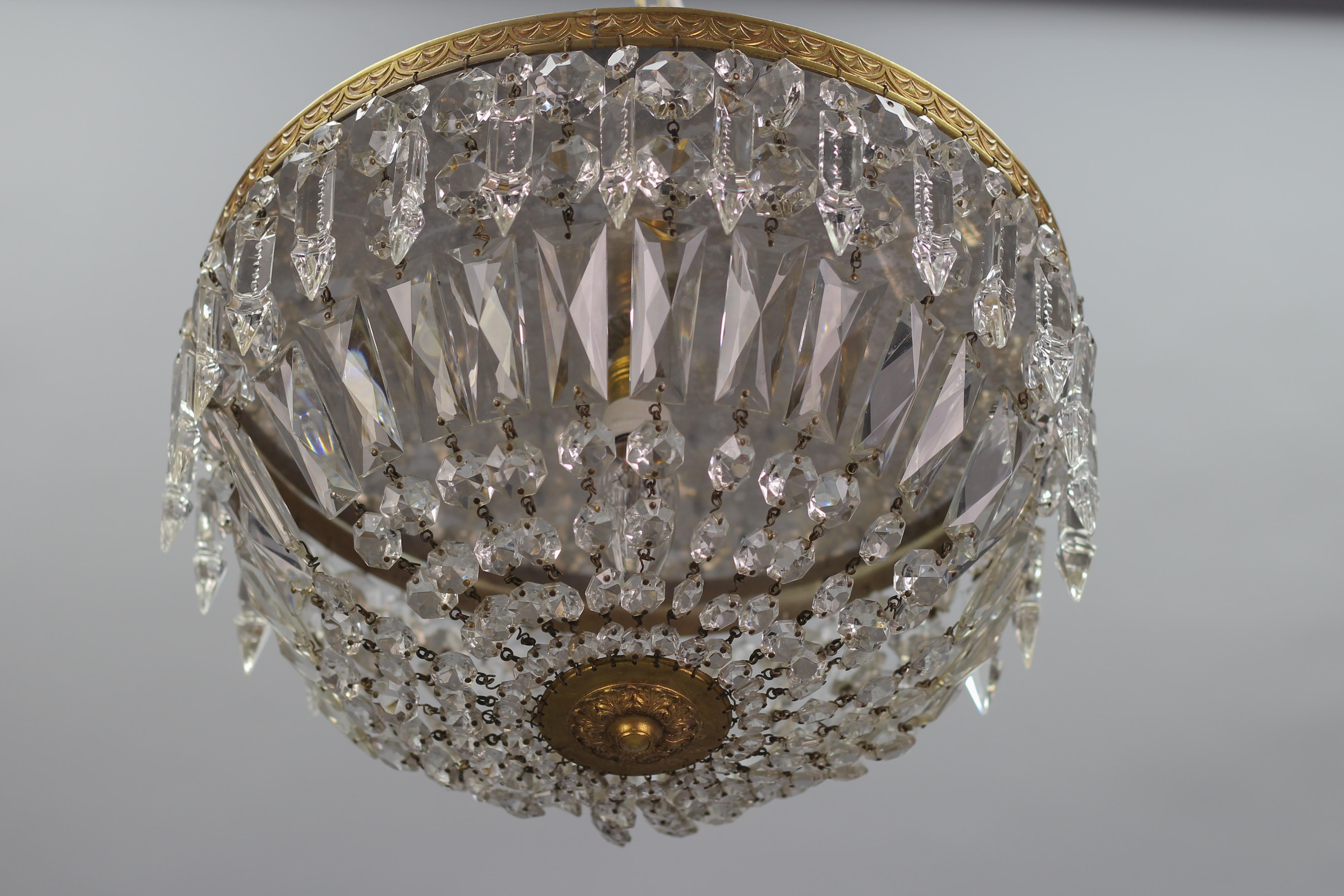 This wonderful Art Deco-style ceiling fixture features clear crystal glass prisms and beads mounted on an ornate brass outer ring, hung with zipper-cut crystal prisms, and centered with a brass finial.
One interior light - one socket for E14 size