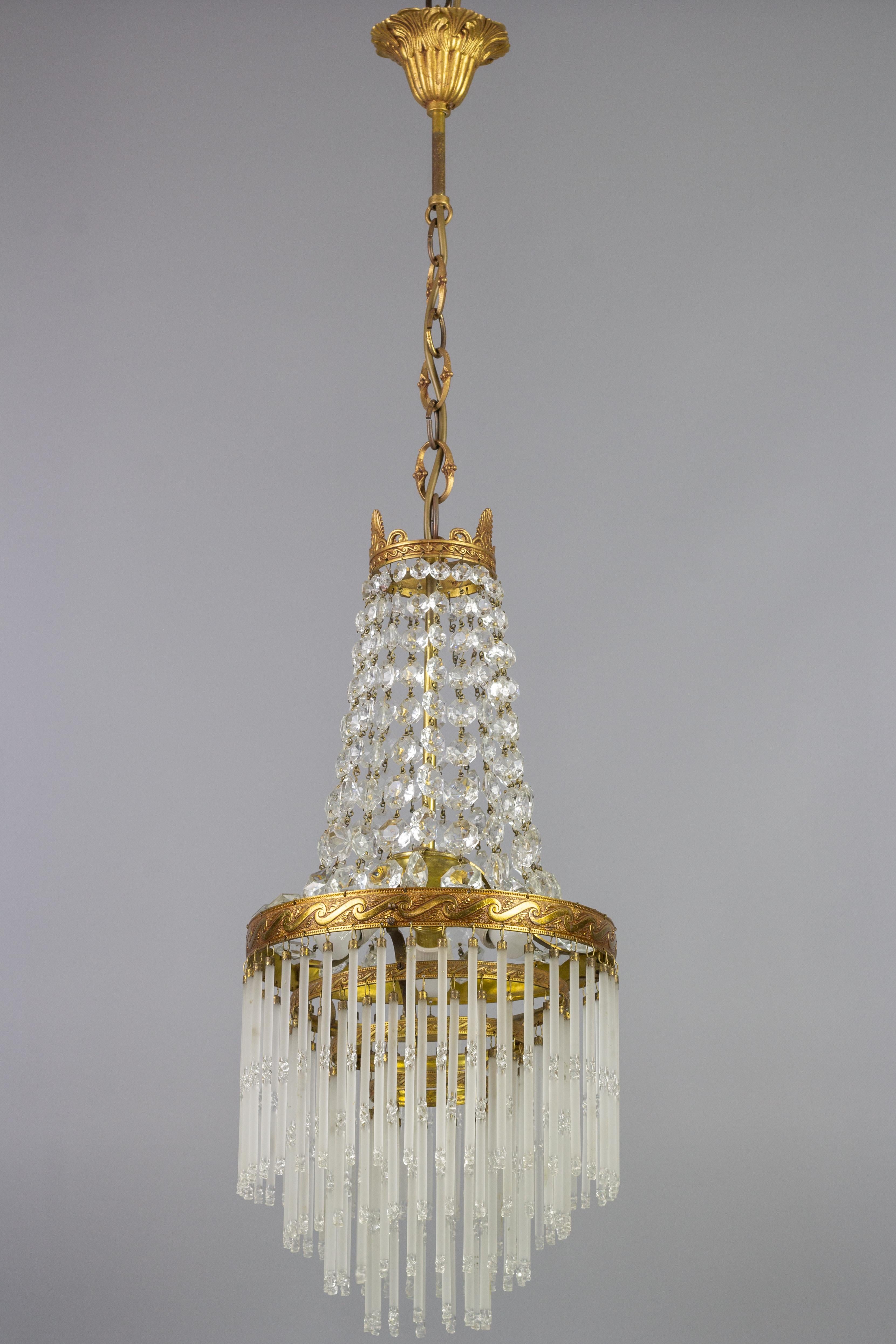 Charming French Art Deco style crystal glass and brass chandelier from the 1950s. This lovely piece has a brass frame hung with chains of crystal glass beads forming a basket and reflecting the light beautifully. Adorned with a brass crown on top