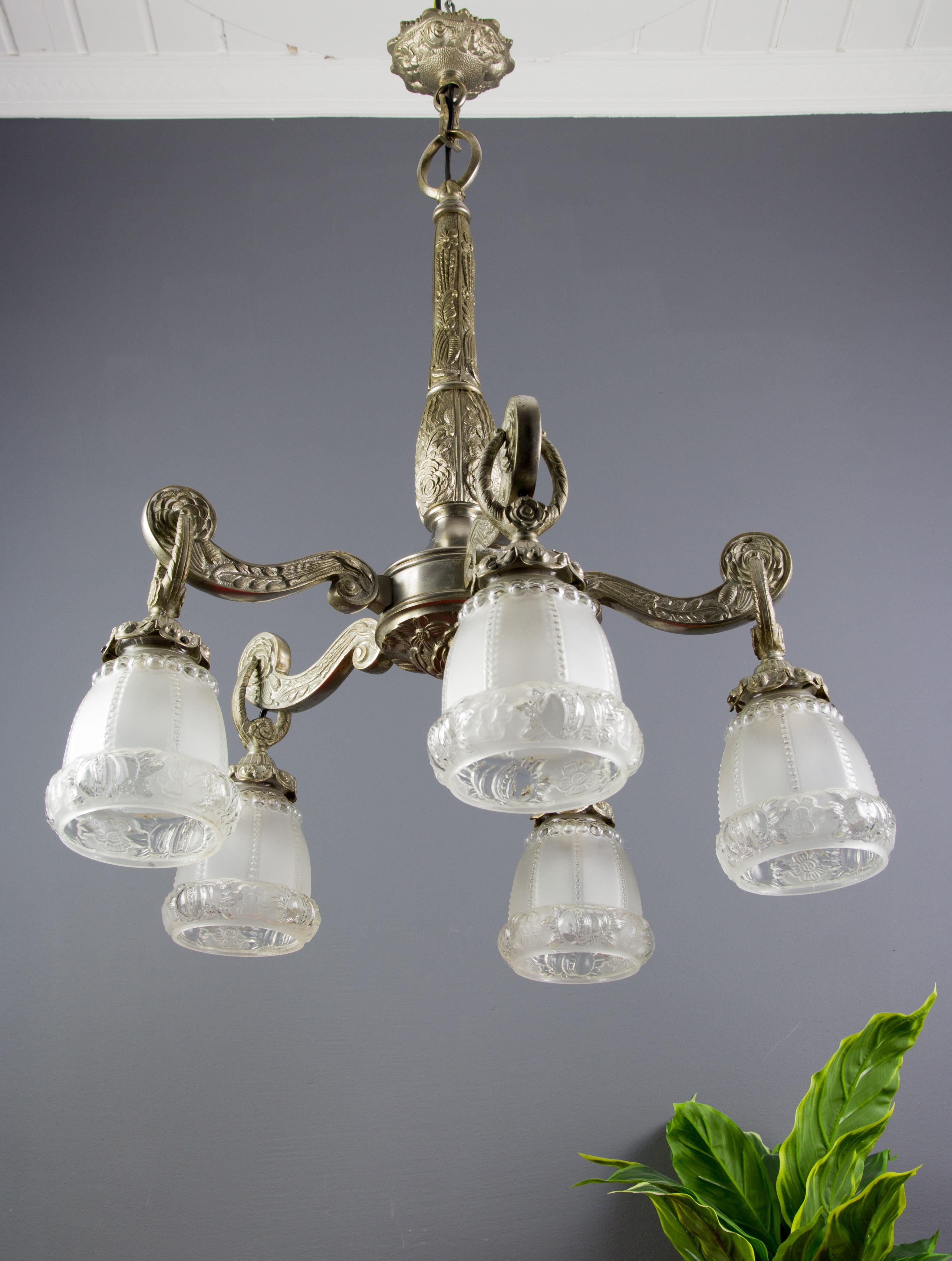 Beautiful Art Deco style bronze chandelier with floral and foliate motifs on arms, stem, and canopy. Five bronze arms, each with frosted floral glass shade and a socket for the E 27 (E26) size light bulb. France, 1930s. 
Dimensions: 
Diameter (with