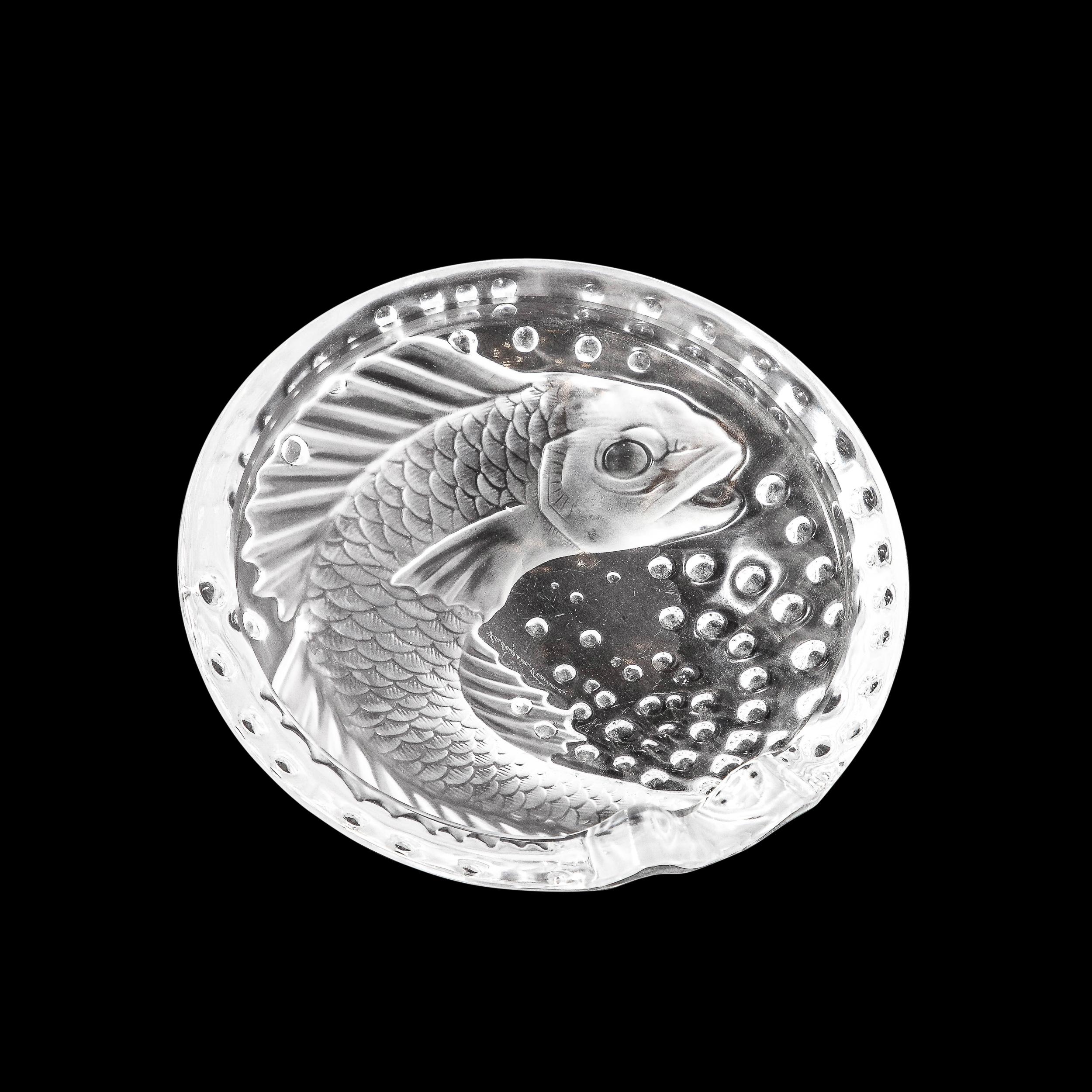 This stunning modernist Art Deco style relief glass decorative dish was realized during the 20th century by the legendary French maker Lalique- one of the finest purveyors of glass products on earth since 1888. This piece features a concave center