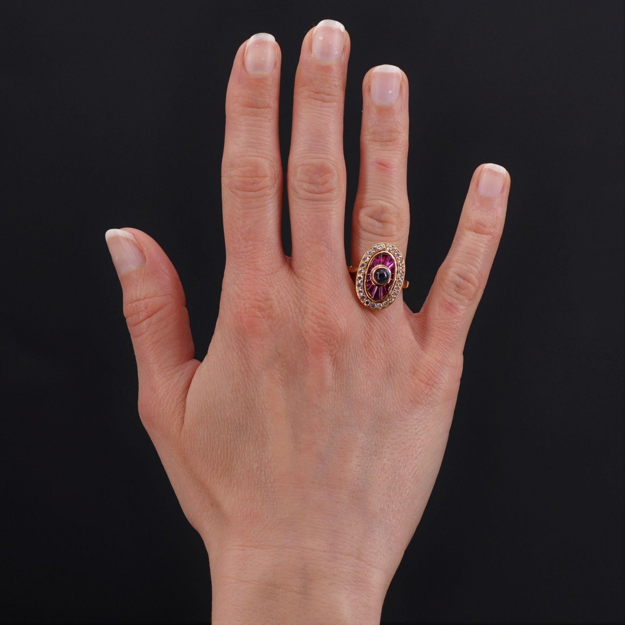 Ring in 18 karat yellow gold, eagle head hallmark.
Art Deco style ring, it is decorated in the center of a radiant calibrated ruby pattern, of a cabochon sapphire in closed setting. The whole is bordered by a surround of modern brilliant-cut