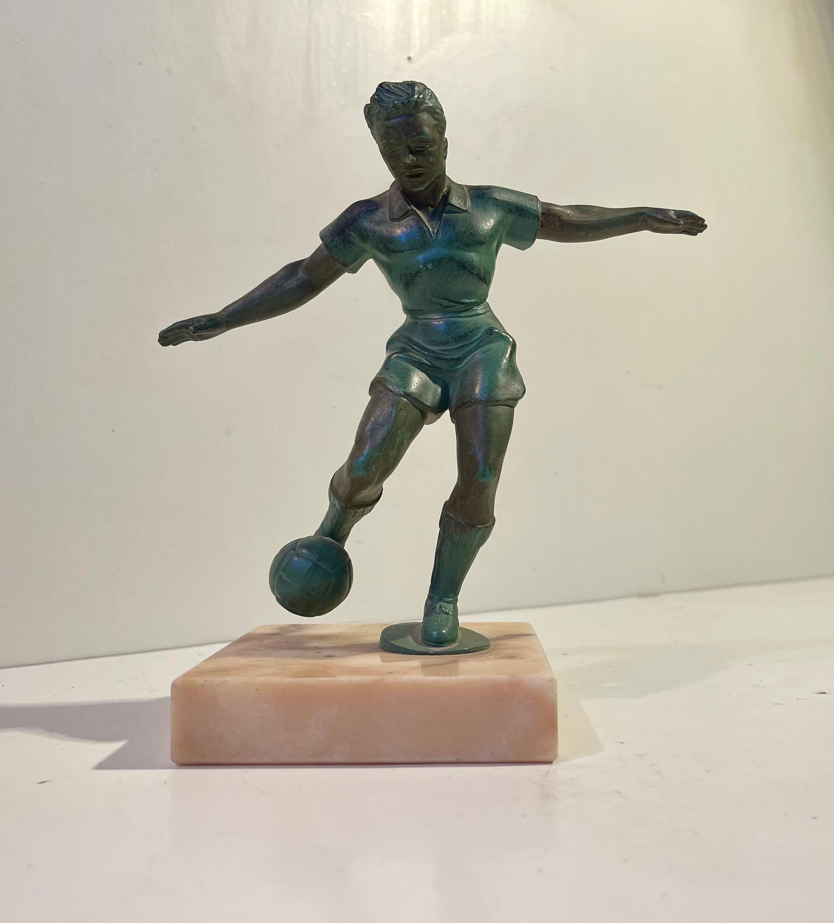 Un'elegante scultura da scrivania francese a forma di calciatore che calcia il pallone in perfetto equilibrio. An He è posizionato su una base di marmo. An He è stato realizzato in bronzo o in metallo bronzato e gli è stata applicata una patina di