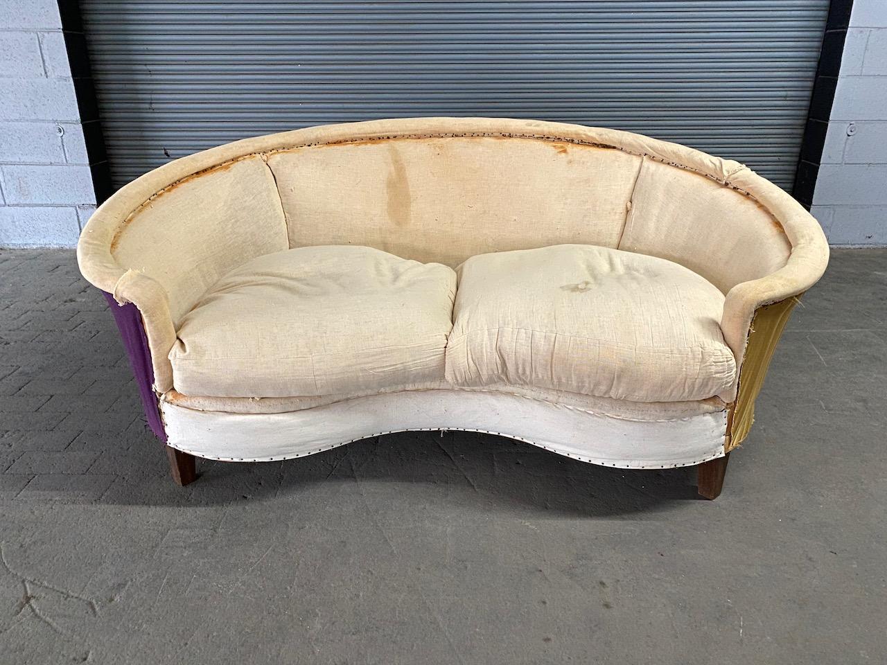 An unusual curved back sofa with loose down filled seat cushions and a tight back, tapered legs that may have been skirted. This sofa will be stunning once upholstered. French 1940s-1950s. 

Sold as is.

Measures: 30.5” H x 68.5” L x 41” D, 17” seat