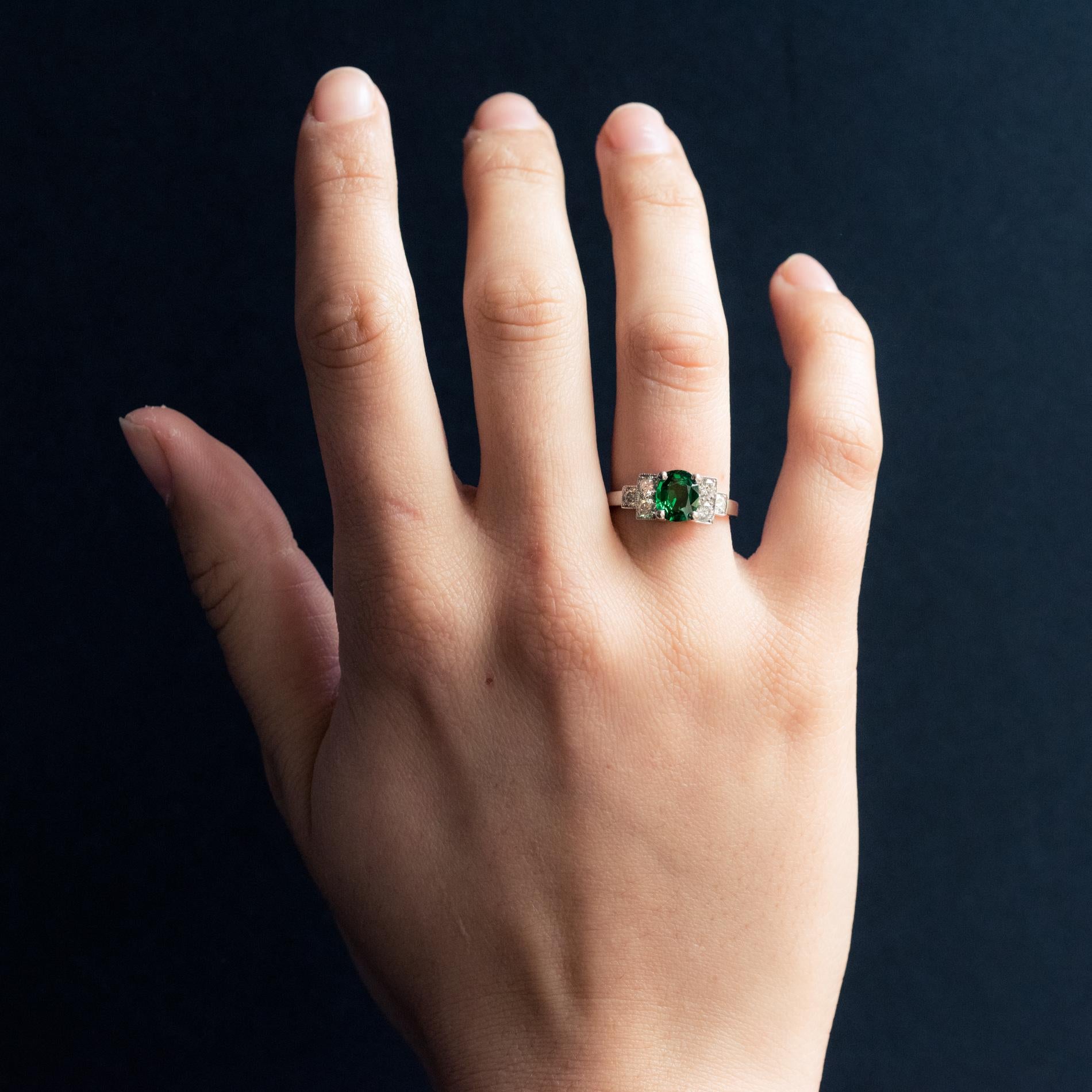 Ring in platinum, dog's head hallmark.
Lovely Art Deco style jewelry, the setting of this ring is set in its center of a green tsavorite garnet. On both sides, a stepped start is set with 2 x 3 modern brilliant-cut diamonds.
Total weight of the
