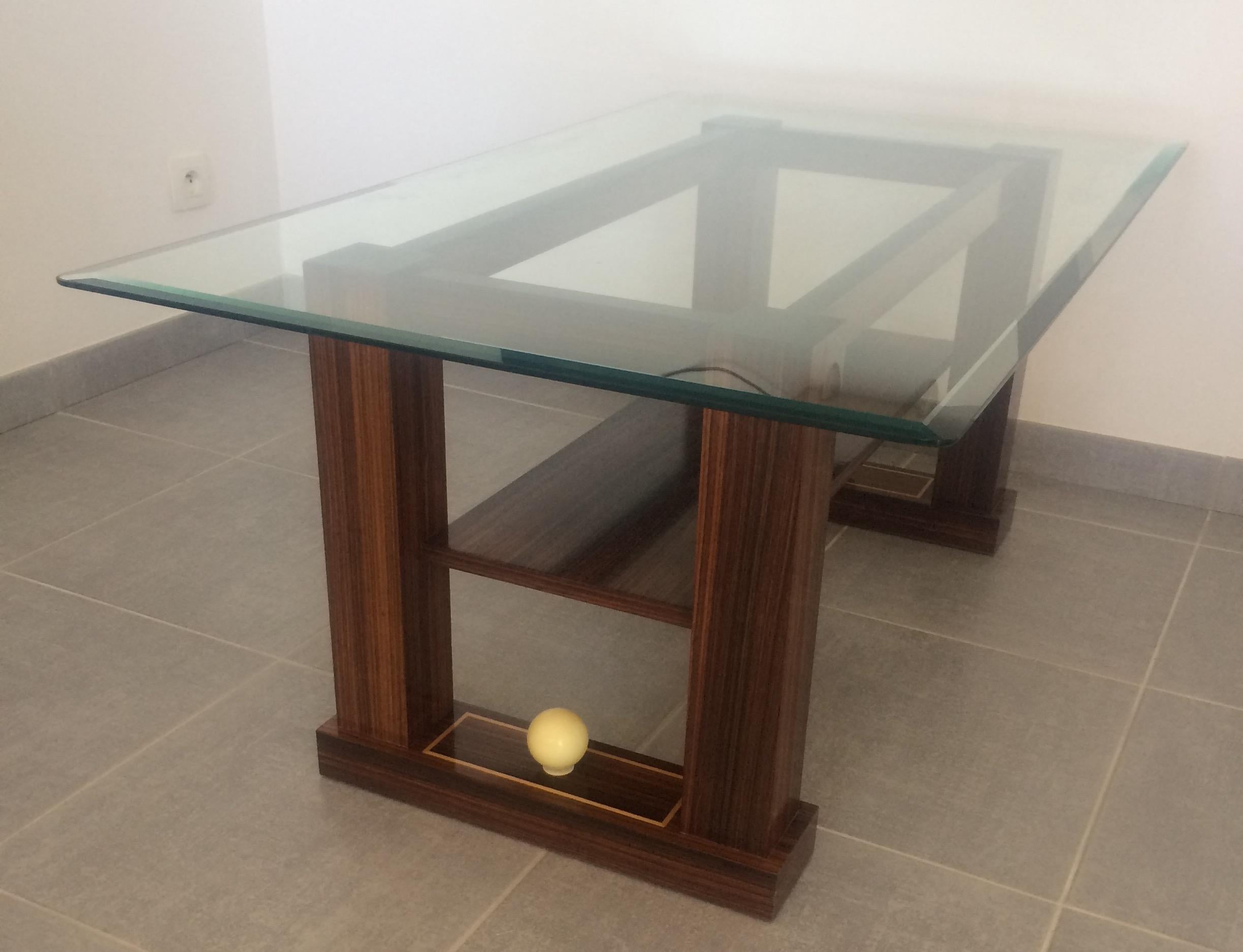 Sleek designed French Art Deco style coffee table with a beveled glass top. 

The table is made of rosewood veneer set on perfectly sturdy legs. Features a centered wooden shelf below the glass top. A base features stretchers accentuated with an