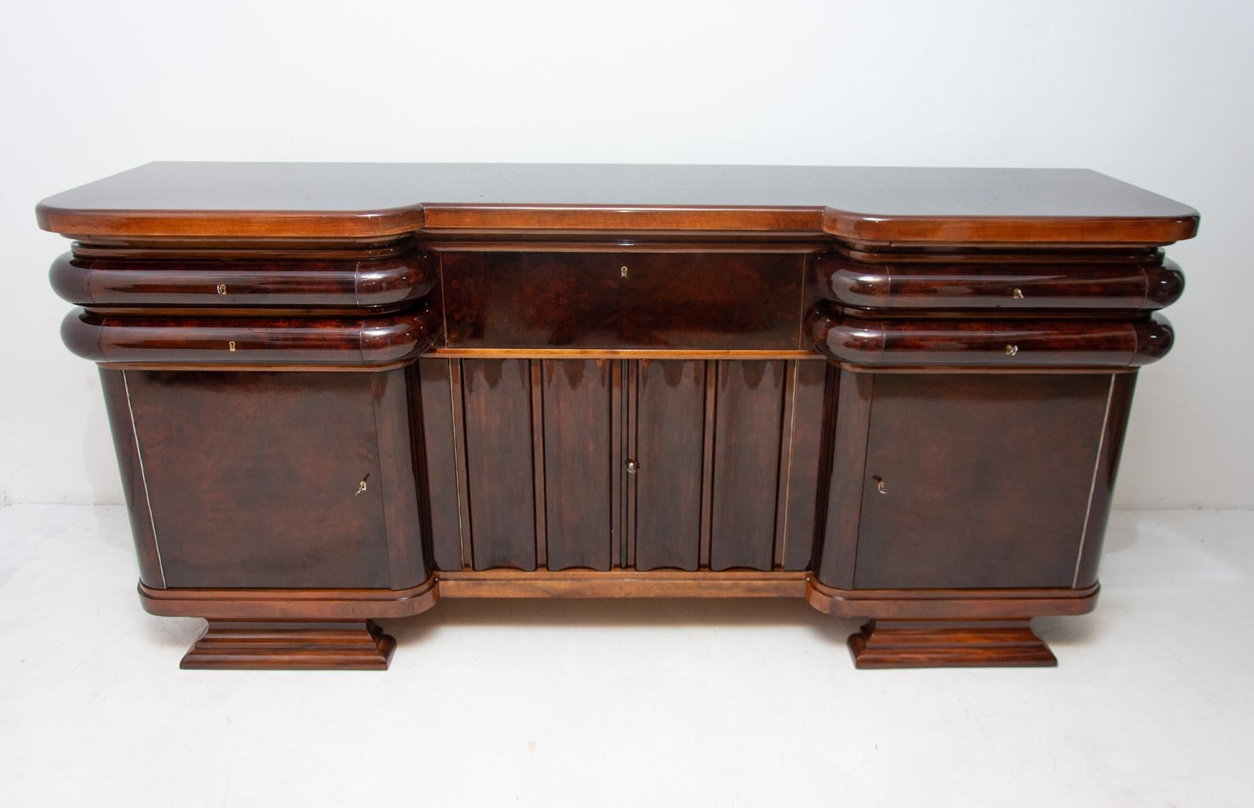 This exceptional sideboard or buffet was made in Bohemia in the 1930s by the famous local furniture company Jan Štícha-Líšov. It´s made of solid wood and veneered in walnut. It features a large storage space and unique rounded shapes of the