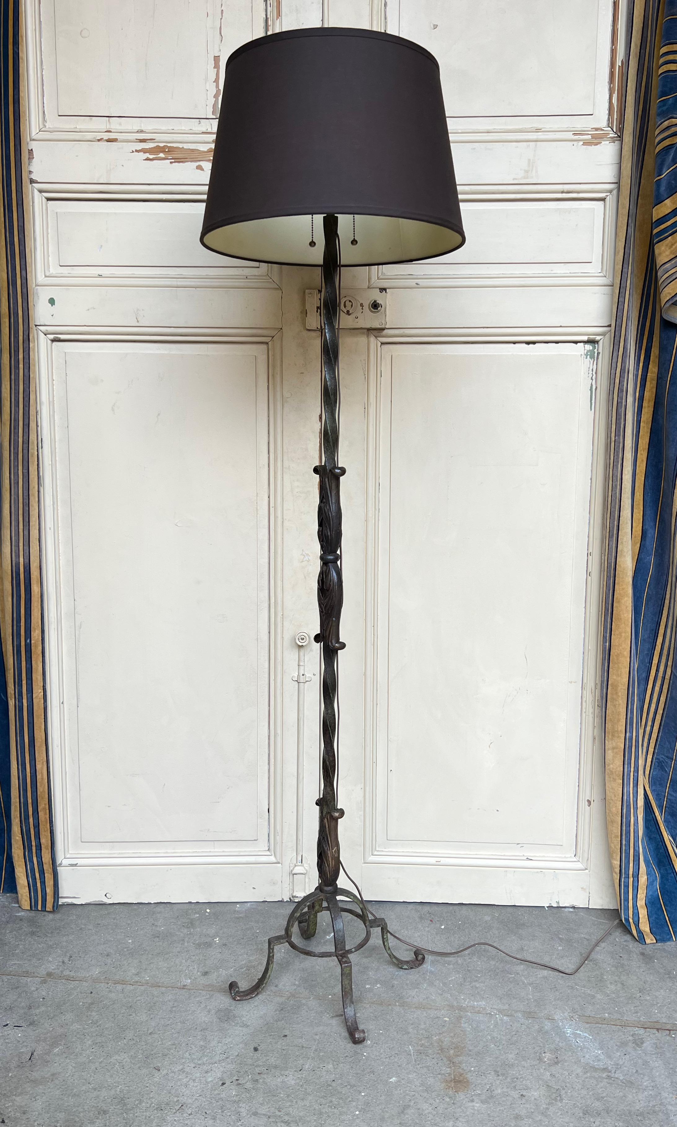 This exquisitely crafted French Art Deco floor lamp is made of solid wrought iron, featuring a vintage green patina with gold accents. The elegant four legged base supports an elaborately twisted stem with stately floral elements. The entire lamp