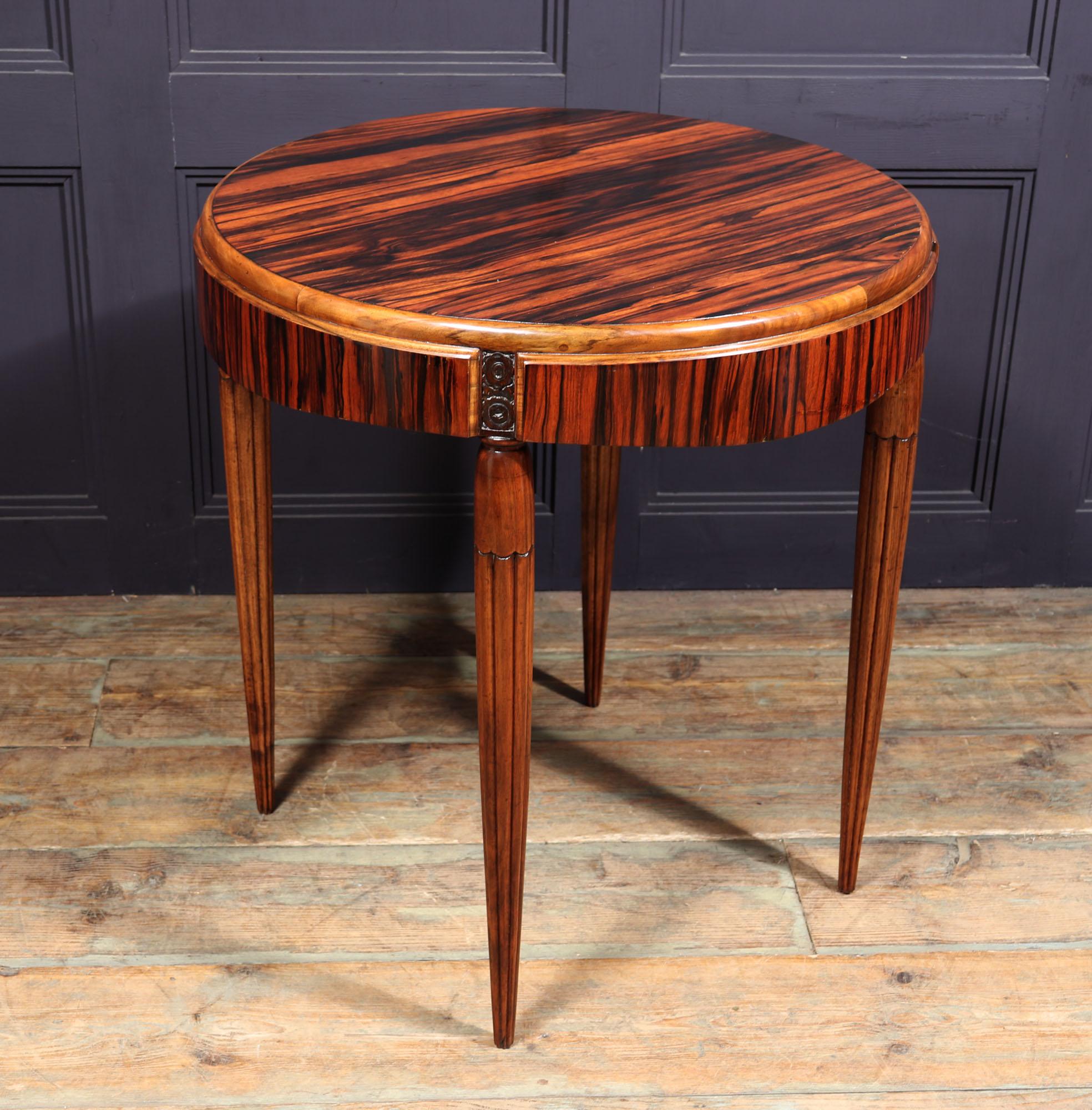 A circular centre or end table produced in solid walnut with Macassar ebony veneers having a gently shaped frieze with floral carved dividers, and standing on turned and reeded legs the table has been restored where necessary and fully polished by
