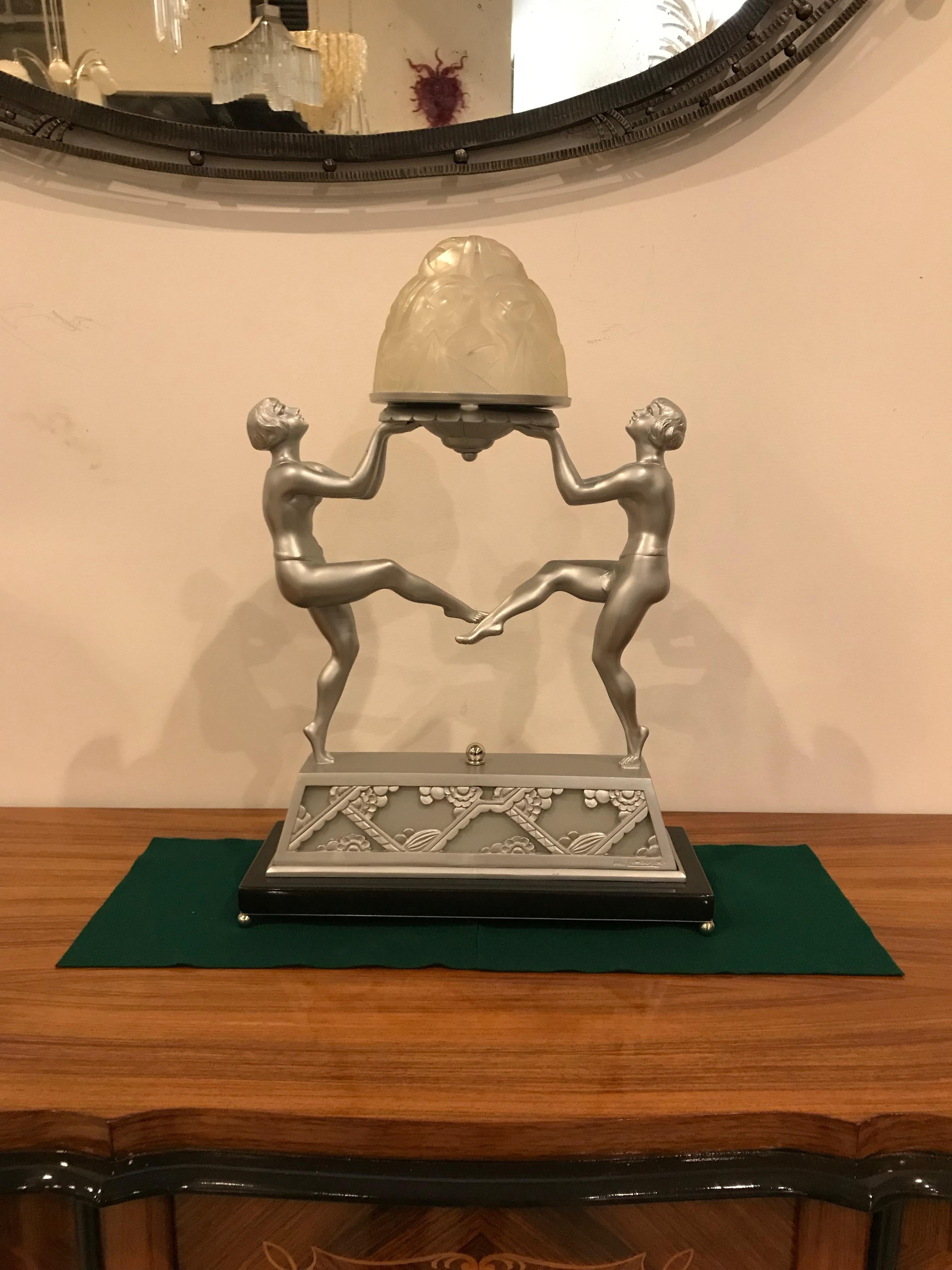 Rare French Art Deco table lamp. Clear frosted glass globe having floral motif signed by Degue. Held on a nickeled bronze decorative design frame signed on the base by Limousin. The Pair of Deco dancing females figures hold the beautiful two tier