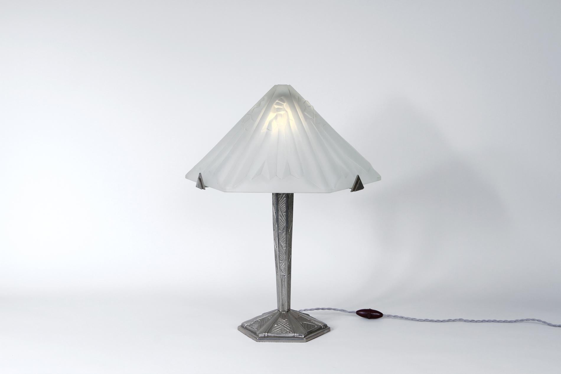 Lámpara de sobremesa original de Degué del periodo Art Déco francés, Circa 1920-1930. El diseño es interesante con la forma de la pantalla de cristal inspirada en el diseño asiático y la base de bronce niquelado trabajada con diferentes decoraciones