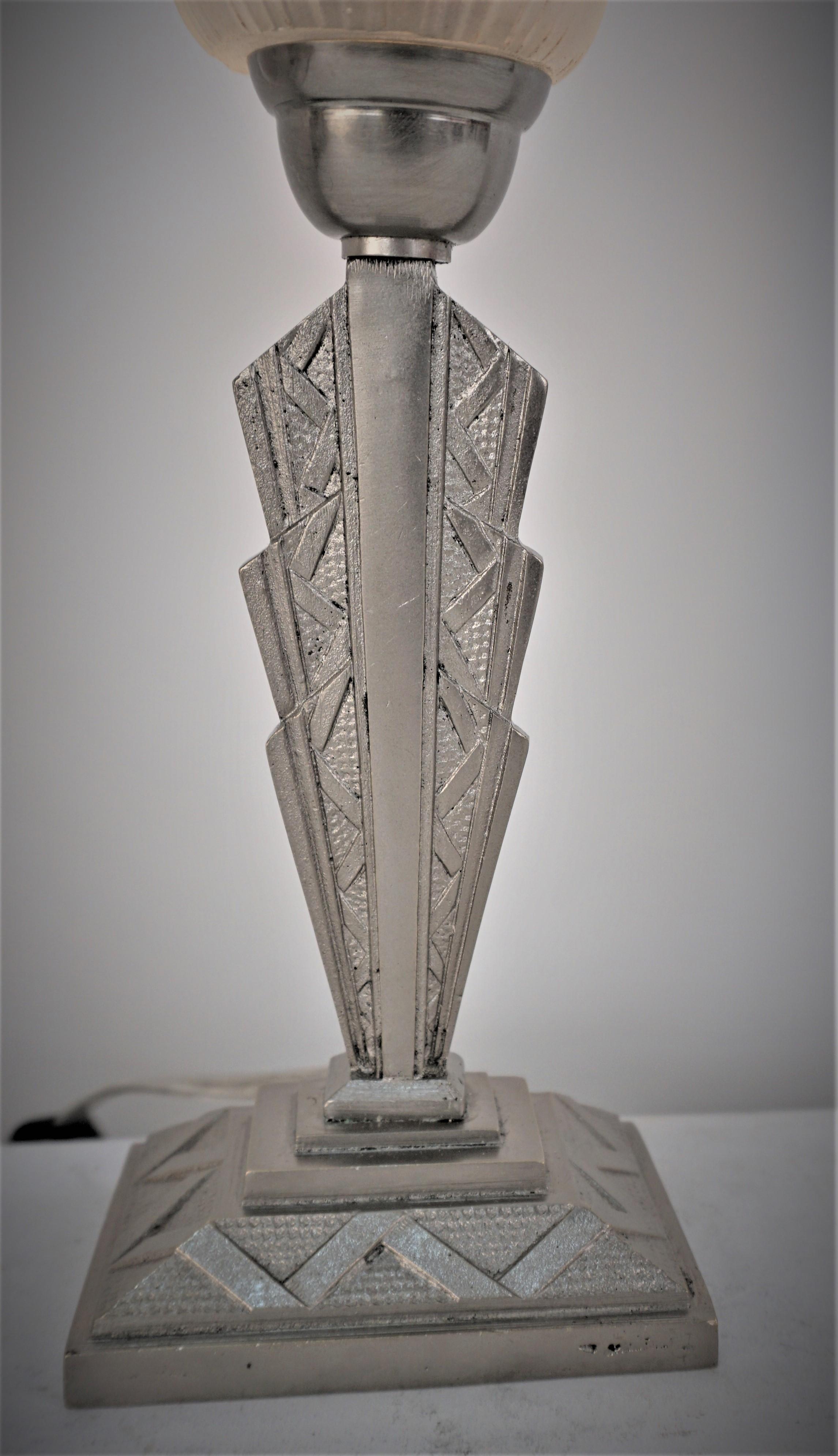 Diseño geométrico de cristal transparente escarchado, lámpara de sobremesa de níquel sobre base oblonga de bronce.
Recableado profesional, bombilla con casquillo E12. 
