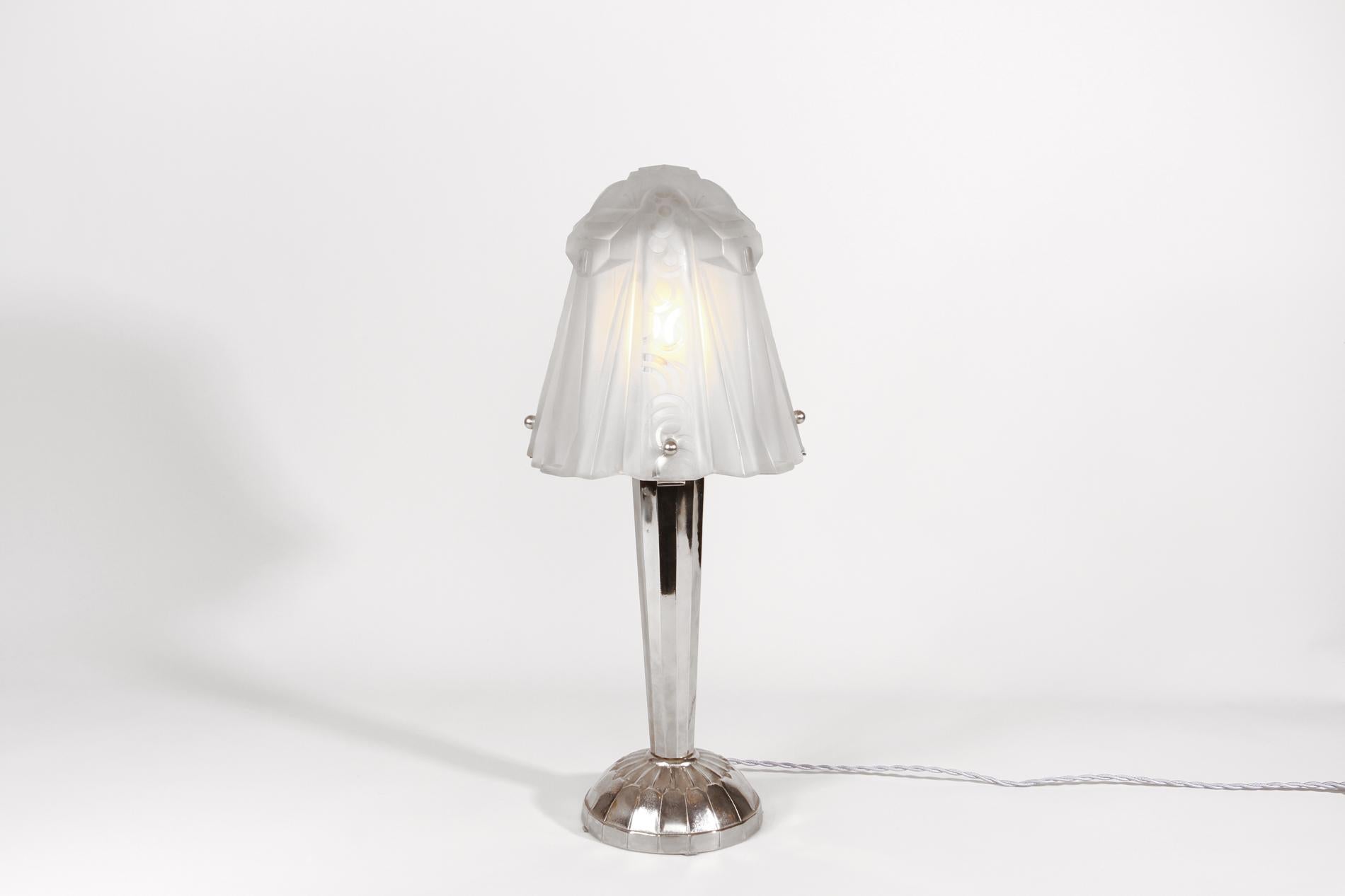 Lampe de table originale Art Déco française par MULLER frères, Circa 1920. La lampe a une base en bronze nickelé et l'abat-jour est en verre moulé avec un décor typique de Muller.  La lampe fait également partie de la documentation 