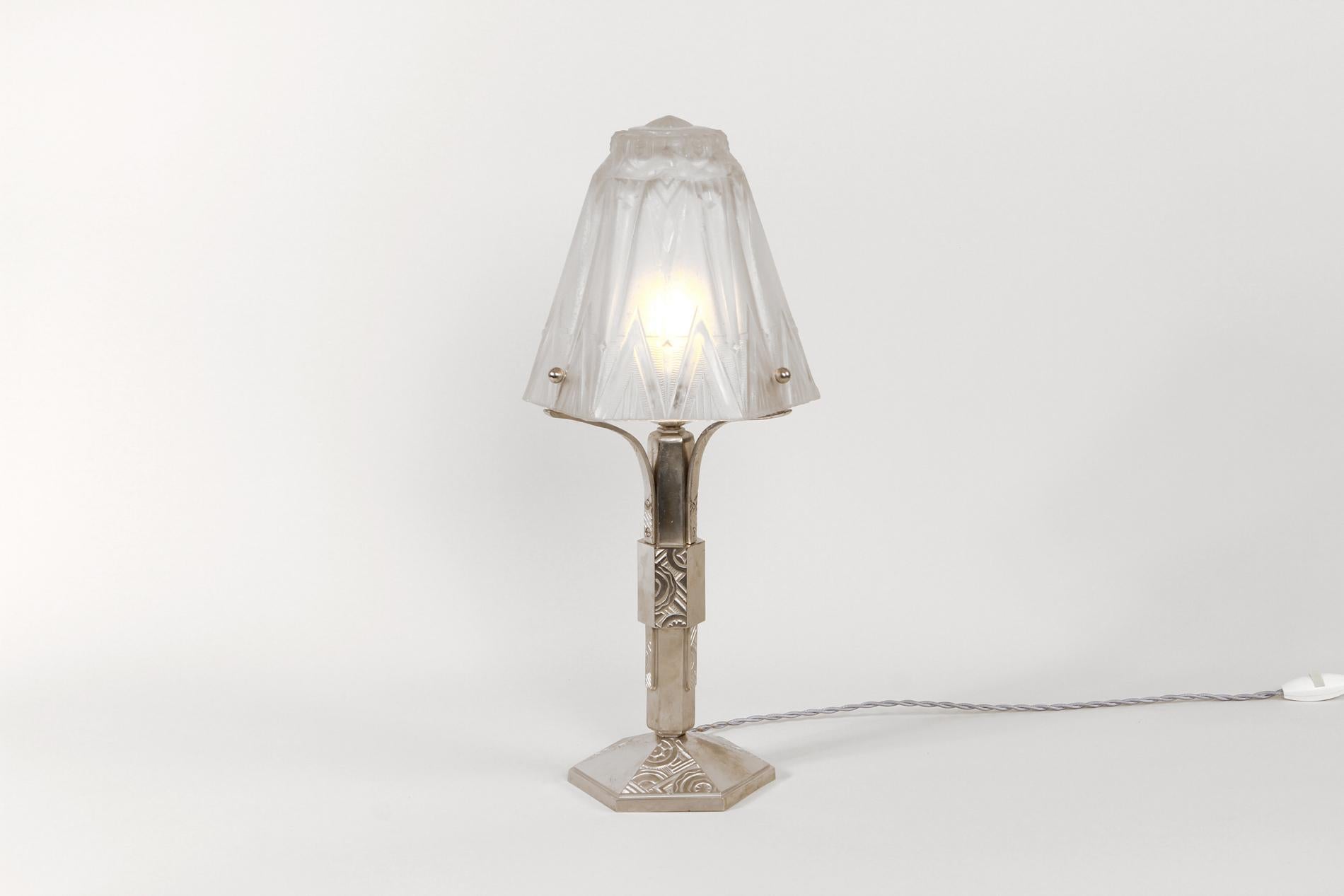 Original table lamp by Muller Frères Luneville, Circa 1930. The lampshade is in glass with geometric decoration and the base in silver nickeled bronze. The lamp is also documented in the catalogue Muller Frères - Verrerie pour liseuses N°5975