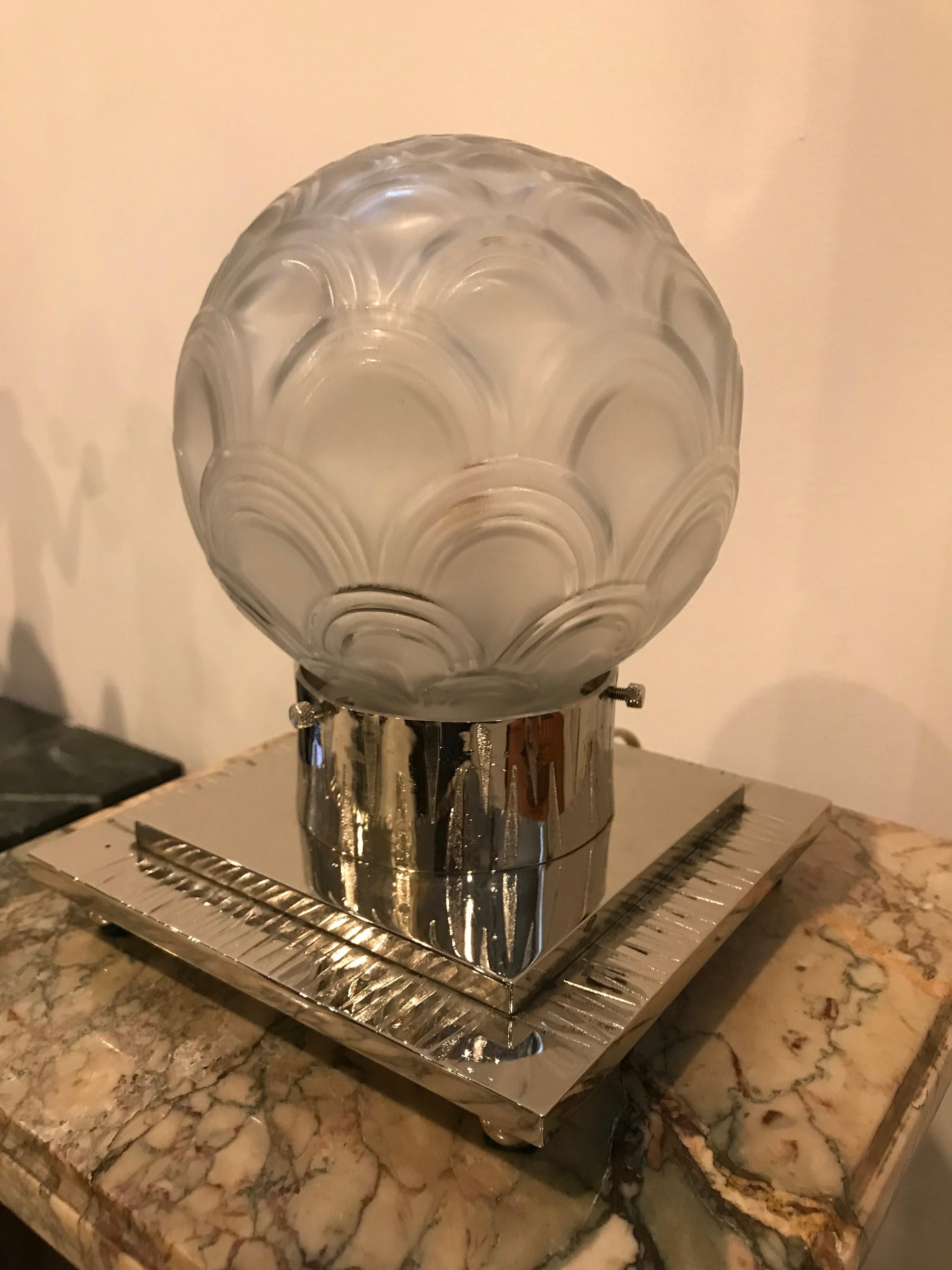 French Art Deco table lamp by Pierre D’avesn. The shade is enhanced by geometric motif in clear frosted glass with polished details. Held by matching geometric polished nickel design frame. Has been rewired for American use with one candelabra