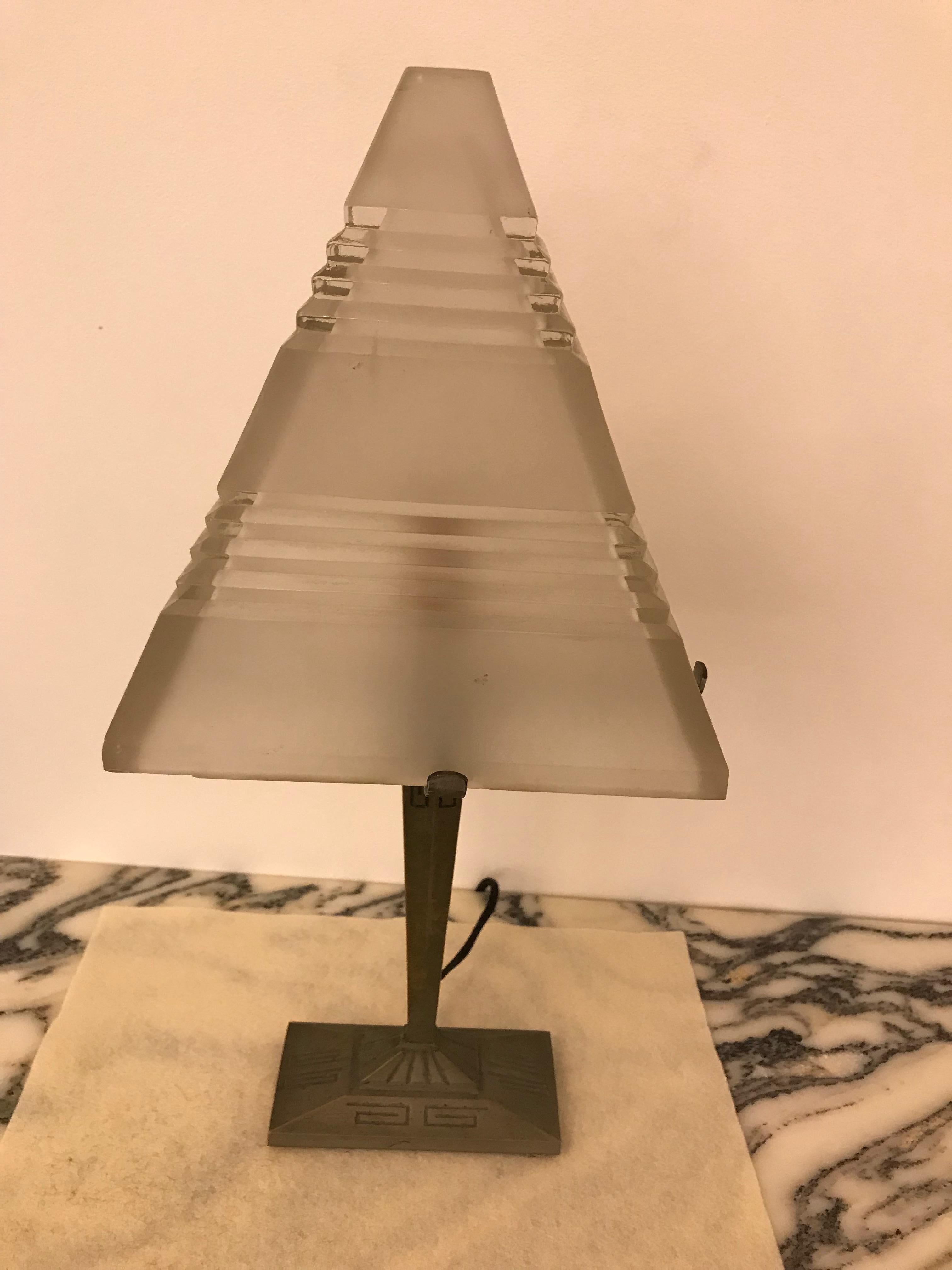 French Art Deco table lamp with triangular glass shade having geometric motif. The glass sits on a brass geometric base. Has been rewired for American use with one candelabra socket. Max watt is 60 watts. The frame can be re plated upon request.