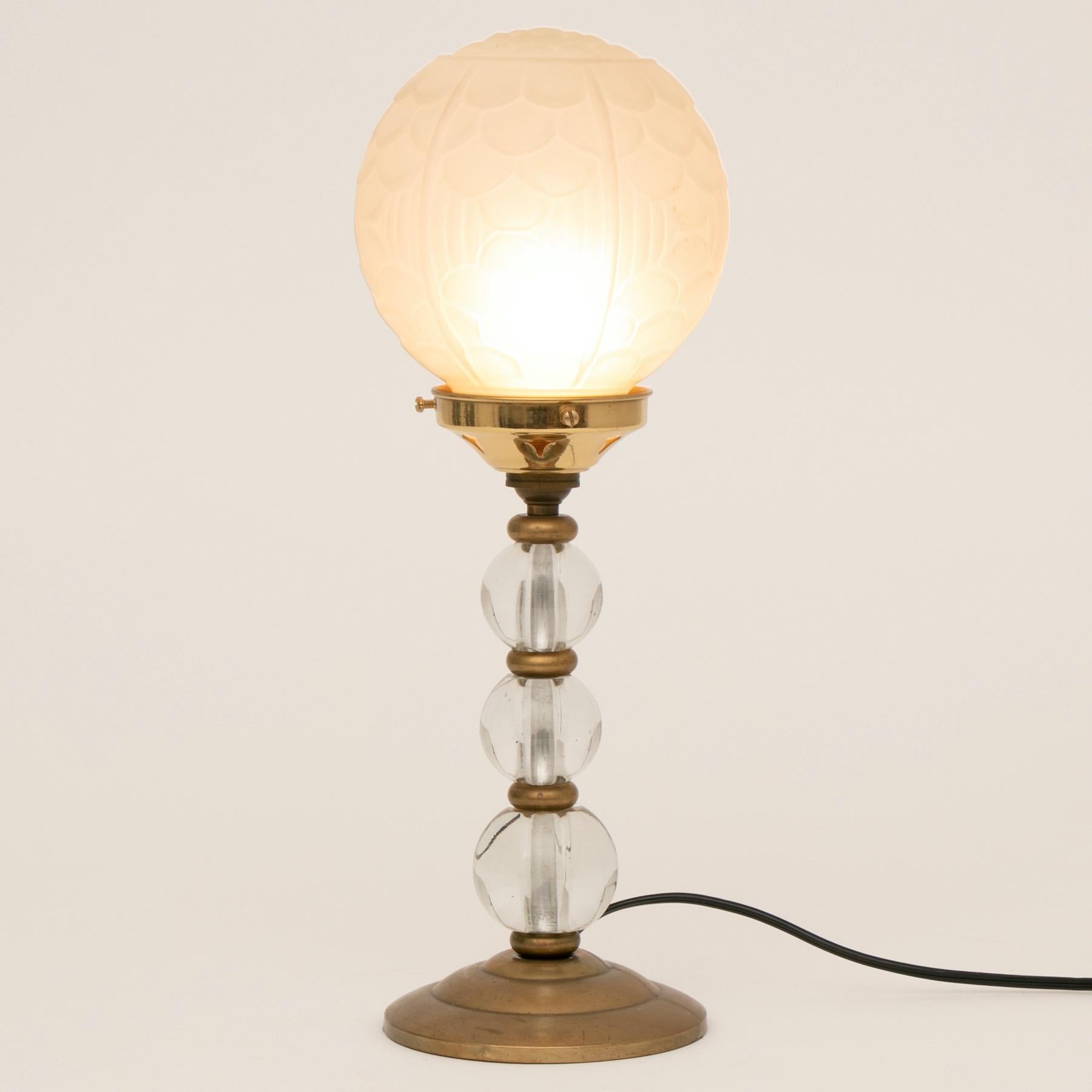 An Art Deco table lamp with brass and glass ball column, and original frosted glass globe shade with moulded Art Deco design
French, circa 1930
Measures: H 40.5cm, W 15cm, D 15cm.