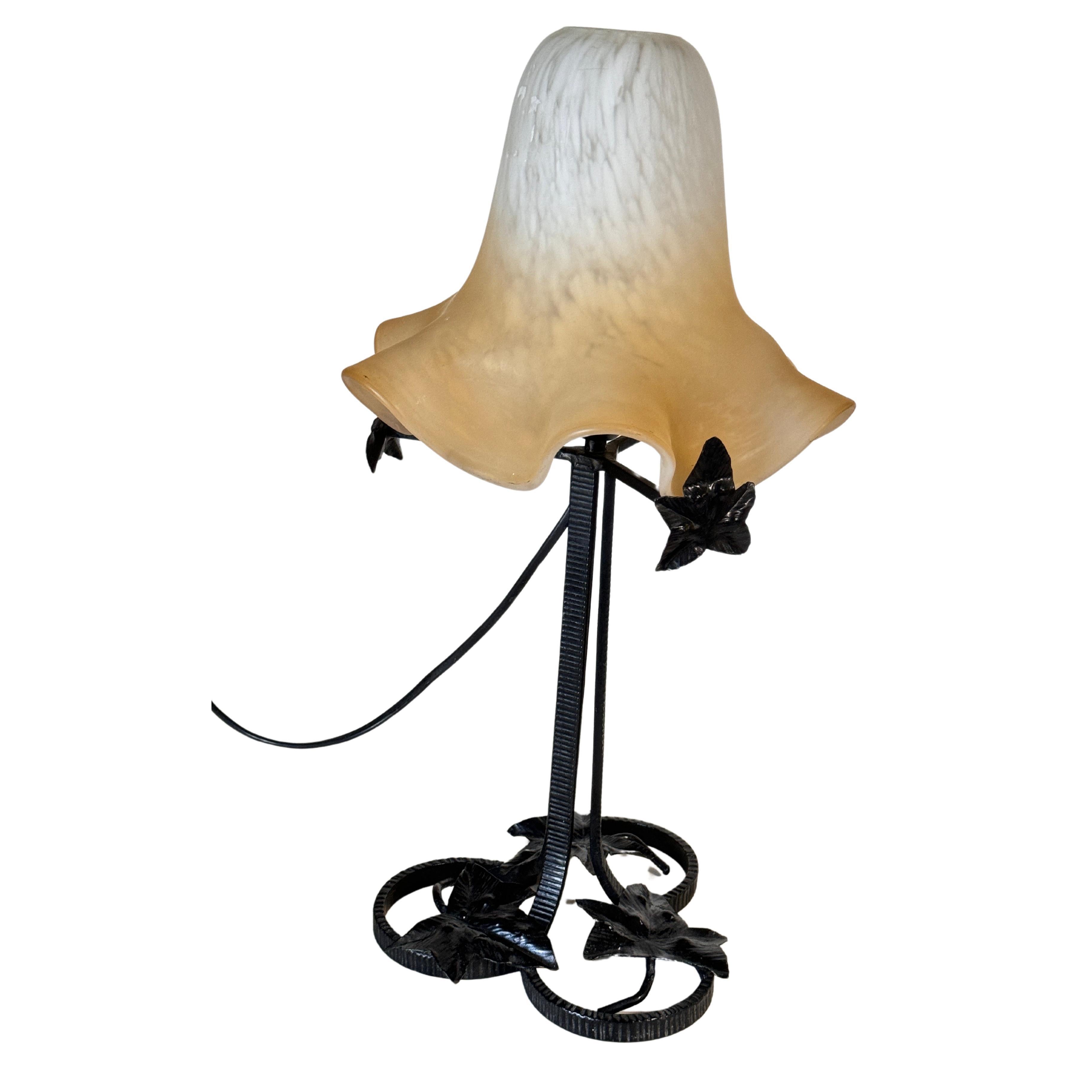 This lamp is a lamp from the Art Deco  style. The shade is Art Deco period, the structure may be later. 
It was made in France in the 1920s for the shade. It is hammered iron. The shade is in Pâte de verre. The electrification is ok. It is a lamp in