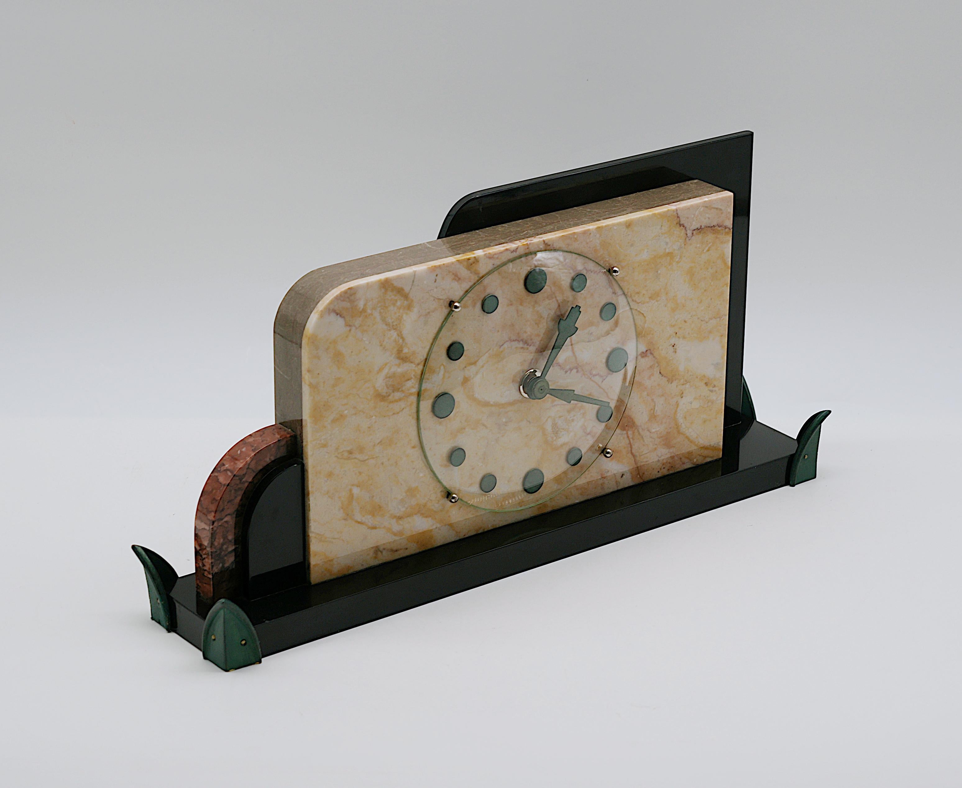 This French Art Deco table/desk clock, circa 1920, is a timeless piece that combines style and functionality. Crafted from marble, glass and bronze, this clock embodies the clean, geometric lines and luxurious materials typical of Art Deco design.