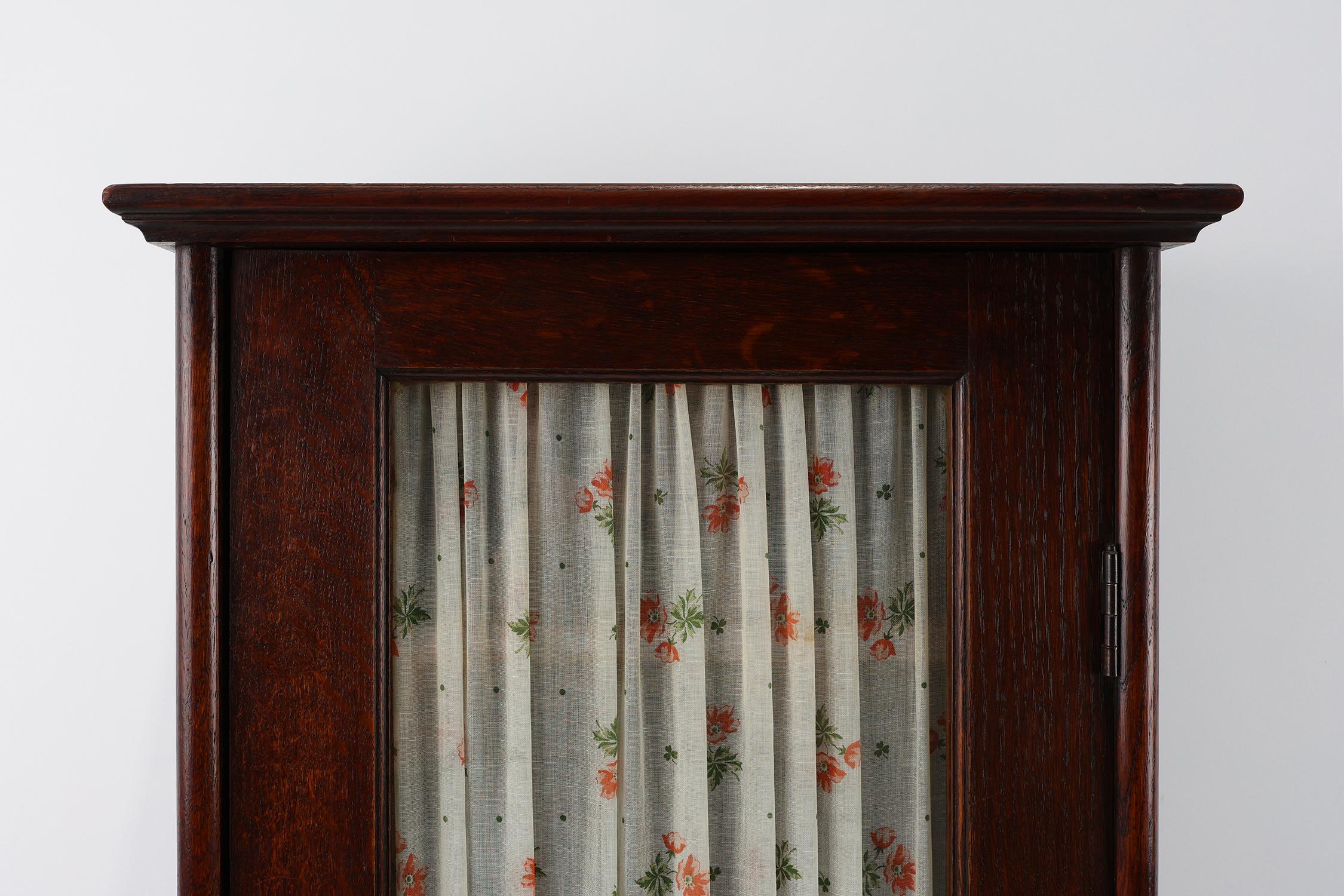 France / 1920 / cabinet / wood, glass, fabric / Art Deco / Mid-century

Timeless tall wooden wall mounted or standing cabinet with one glass door and underneath a hidden storage compartment. Designed in Art Deco style in the 1920s in France. With